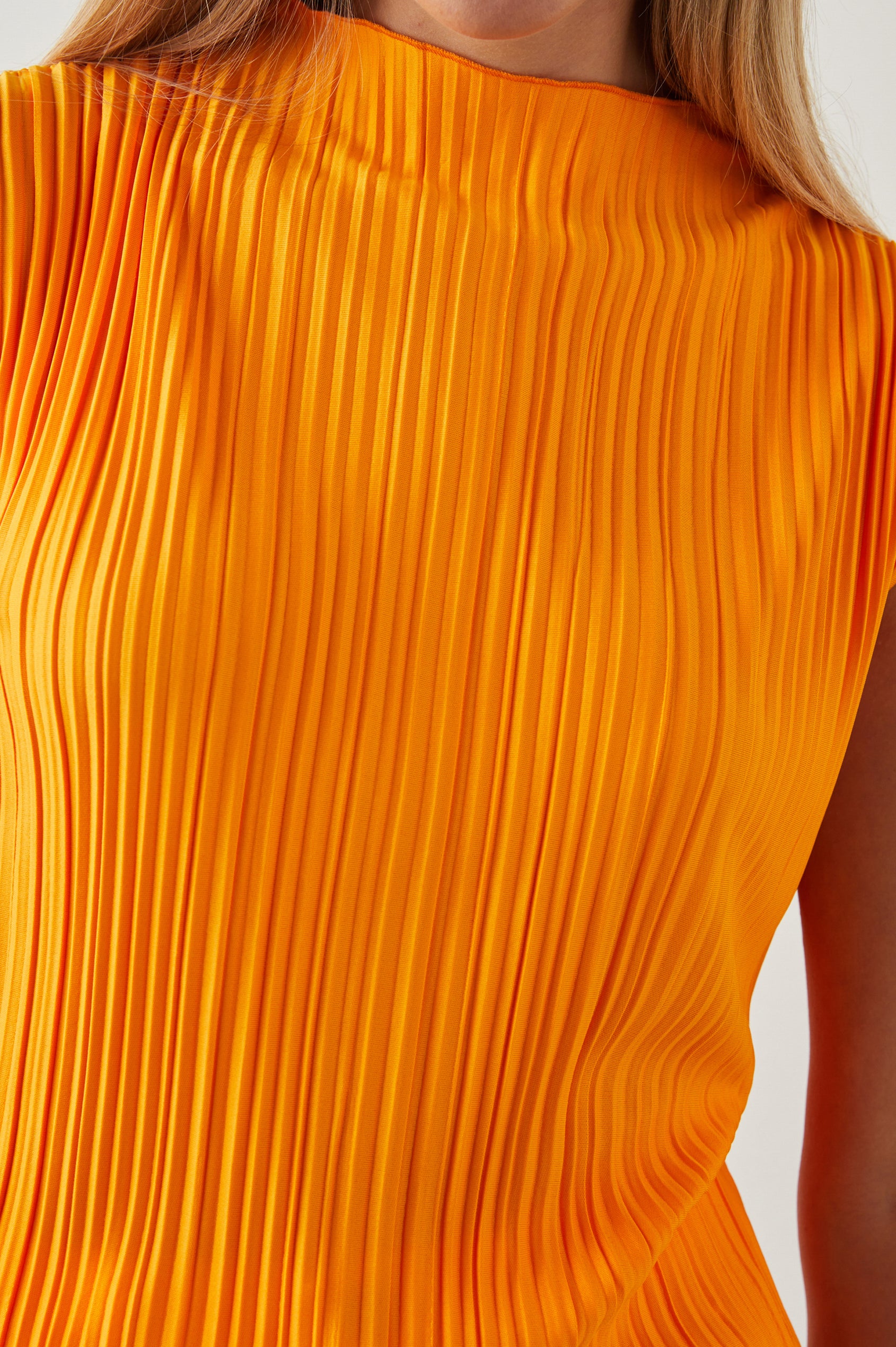 Trea Sleeveless Top with a Mock Neck and Pleated Texture in Marigold Colorway - Front View Featured on Model