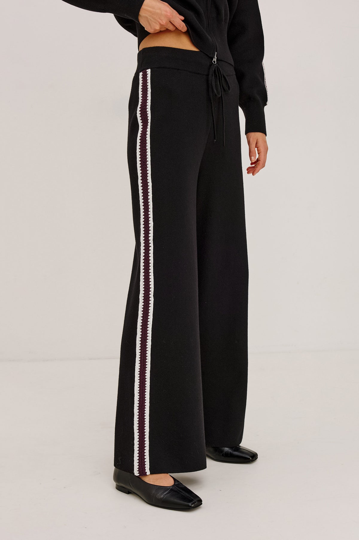 Tucker Pant in Soft Structured Knit With Wide Straight Legs, Drawstring Waist Ties, and Crochet Side Stripes in Black Merlot Stripe - Upper Body Front View Featured on Model.