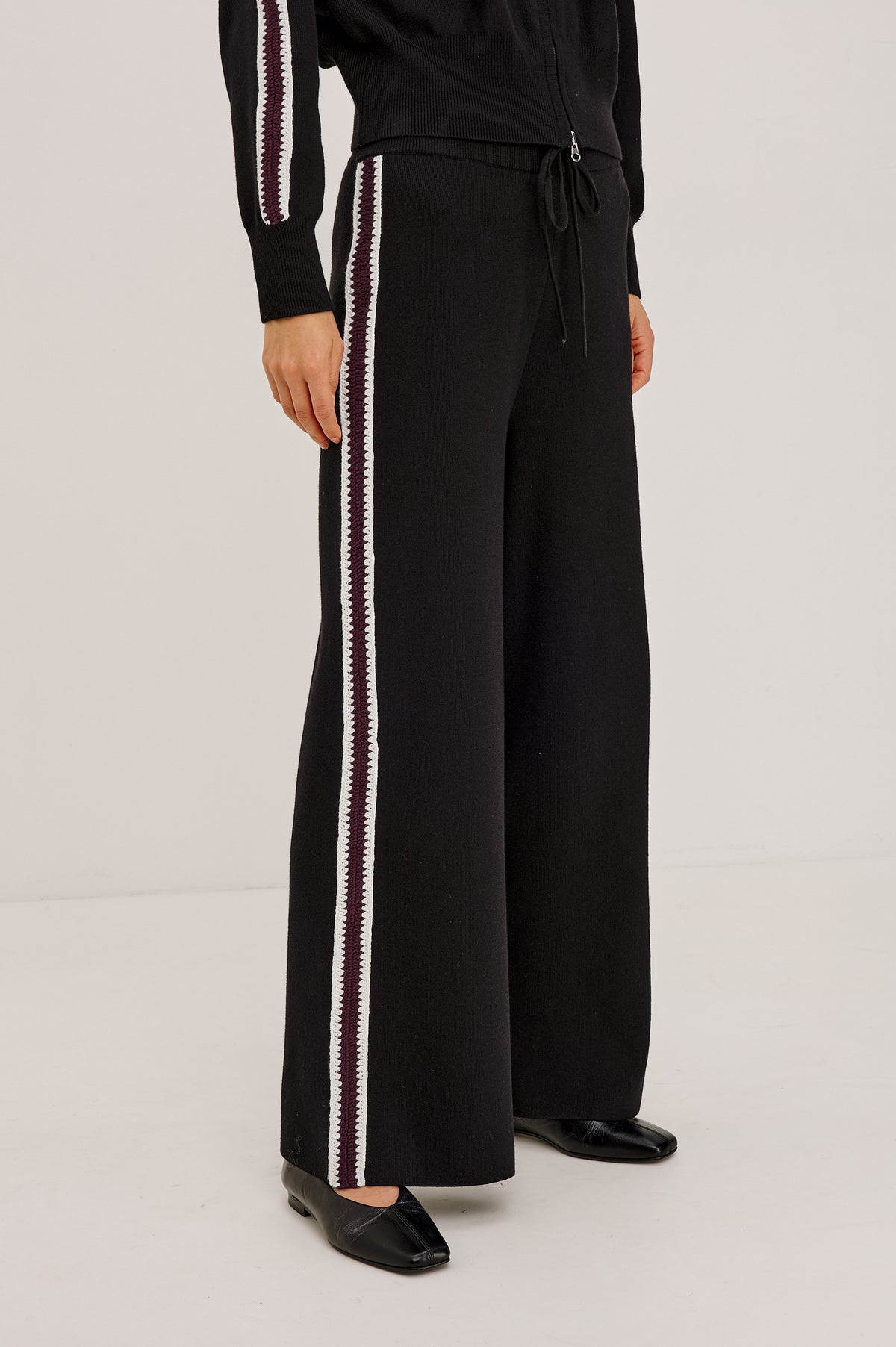 Tucker Pant in Soft Structured Knit With Wide Straight Legs, Drawstring Waist Ties, and Crochet Side Stripes in Black Merlot Stripe - Front View Featured on Model.
