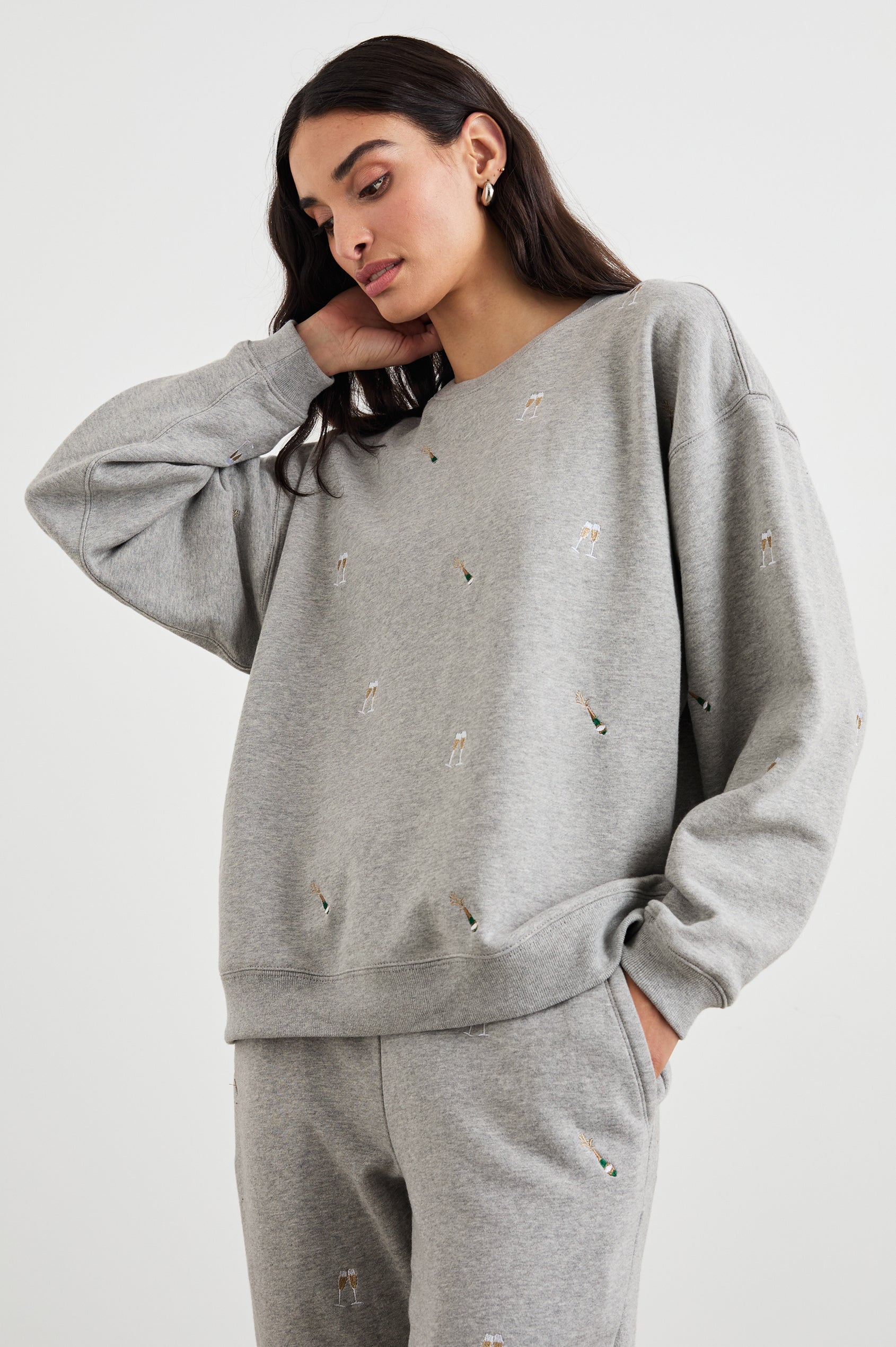 The Varsity Sweatshirt with a Crew Neck and embroidered Champagne Glasses in Champagne Embroidery Colorway, on light grey - Front View Featured on Model 
