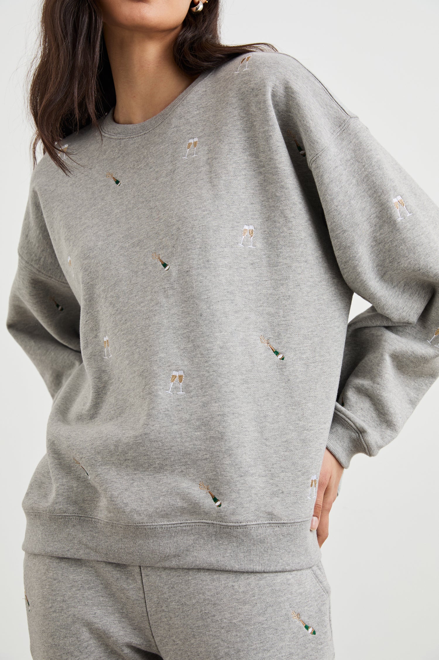 The Varsity Sweatshirt with a Crew Neck and embroidered Champagne Glasses in Champagne Embroidery Colorway, on light grey - Front View Featured on Model 