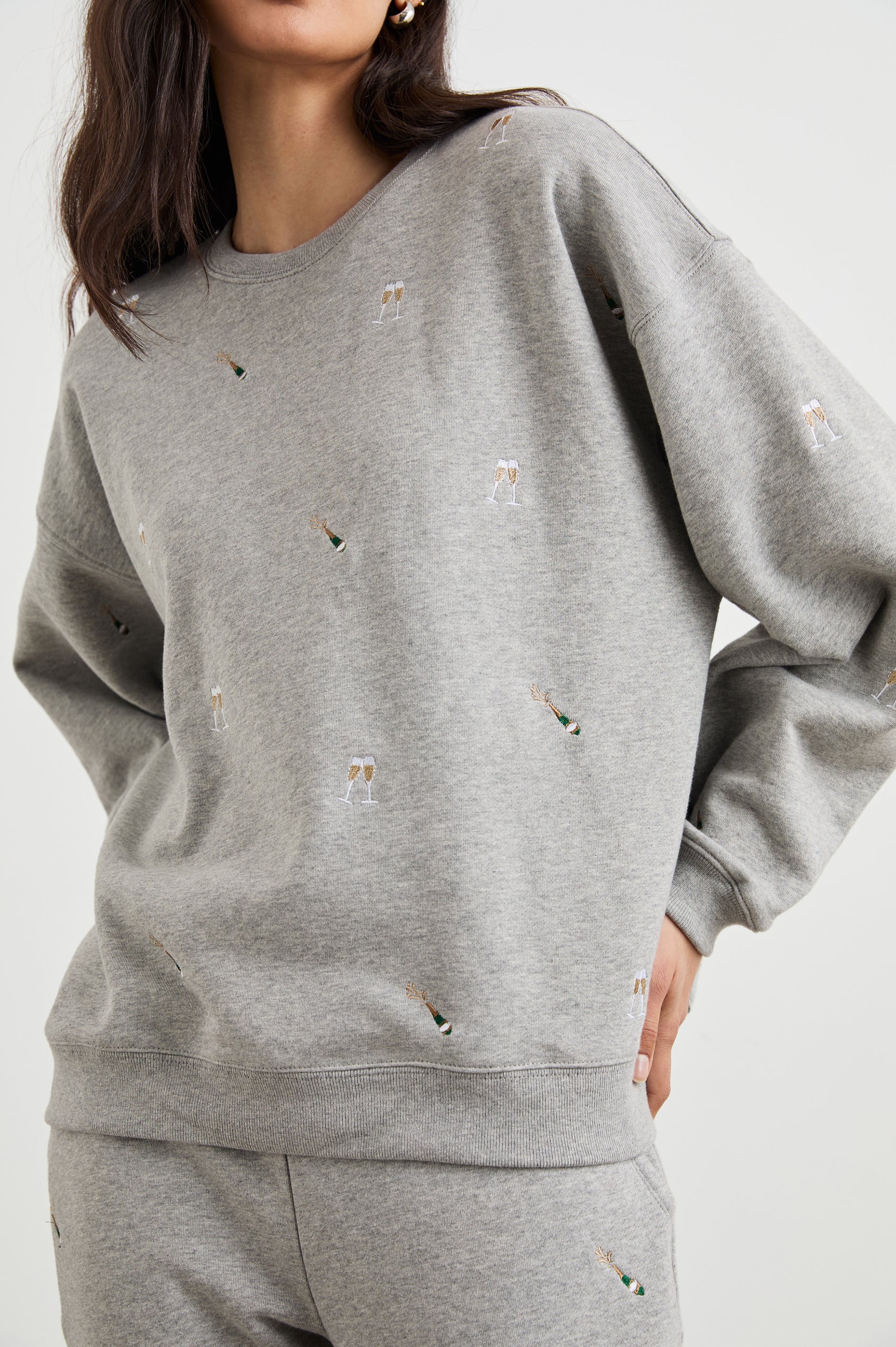 The Varsity Sweatshirt with a Crew Neck and embroidered Champagne Glasses in Champagne Embroidery Colorway, on light grey - Front View Featured on Model 