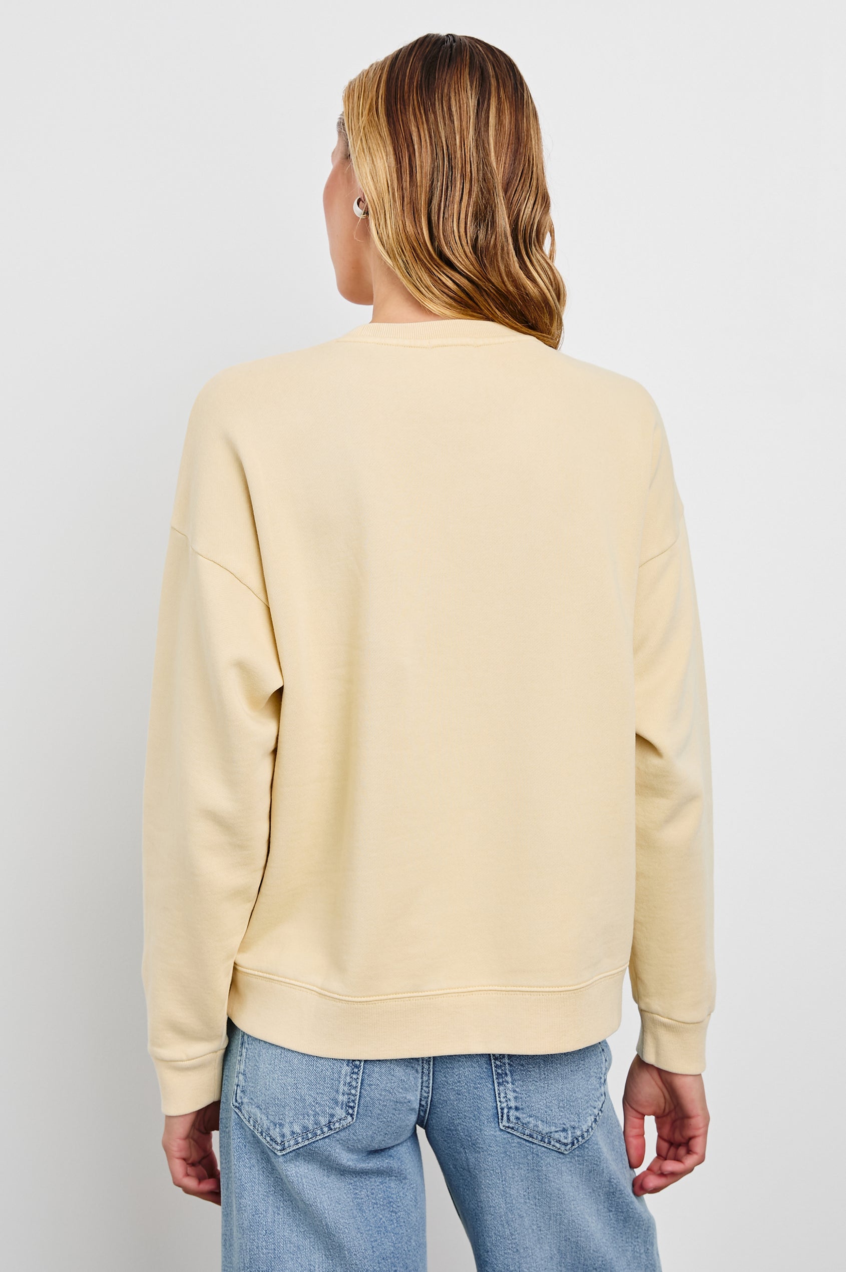 The Varsity Sweatshirt with a Crew Neck and Gold Glitter Text states Los Angeles Rails in Los Angeles Gold Glitter Colorway, on pale yellow - Back View Featured on Model 