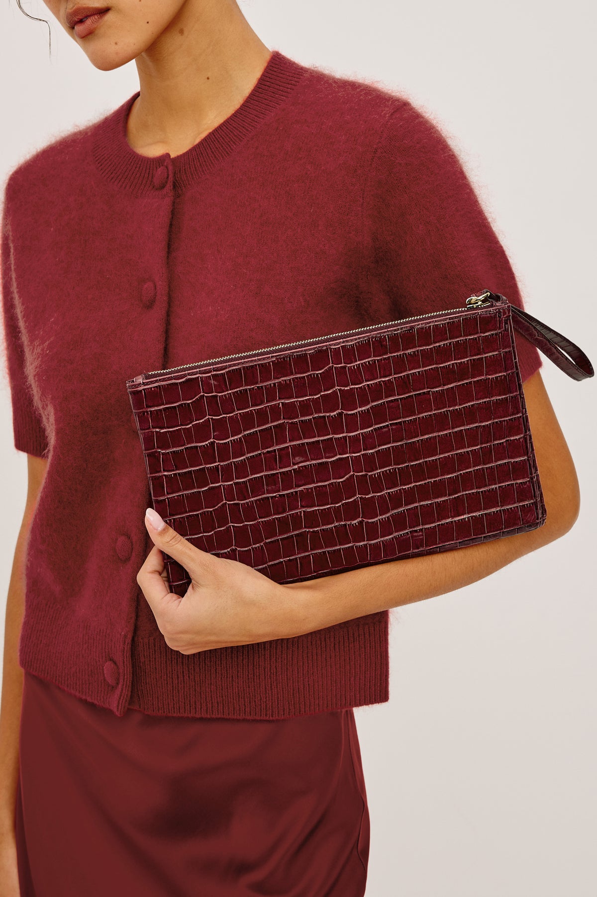 Verona Clutch Bag in Croc-Embossed Leather With Attached Wristlet Strap, Top Zip Closure, and Interior Slip Pocket in Burgundy Croc Embossed Colorway - Close Up Product View Featured