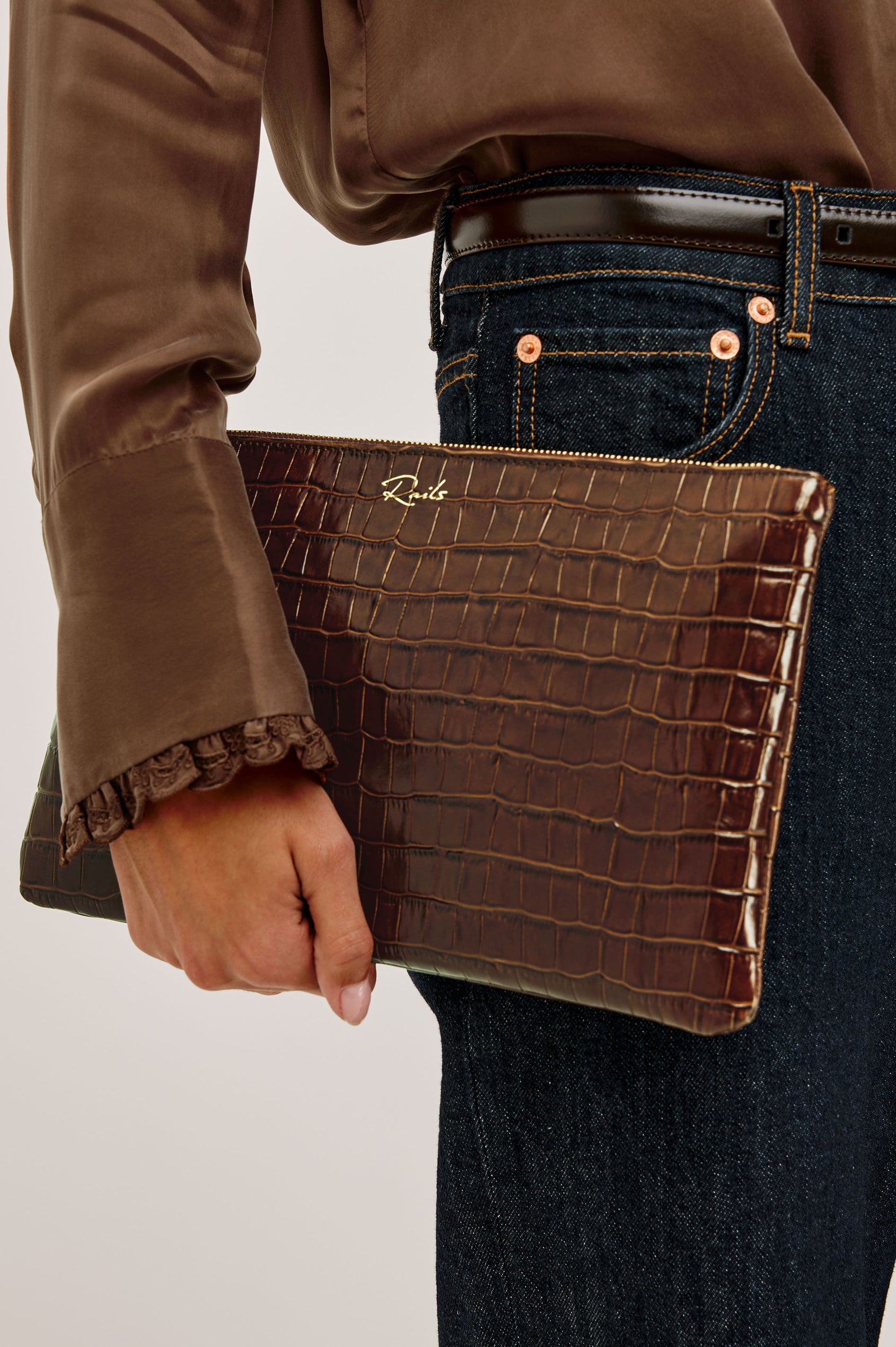 Verona Clutch Bag in Croc-Embossed Leather With Attached Wristlet Strap, Top Zip Closure, and Interior Slip Pocket in Brown Croc Embossed Colorway - Mid Body Side View Featured on Model
