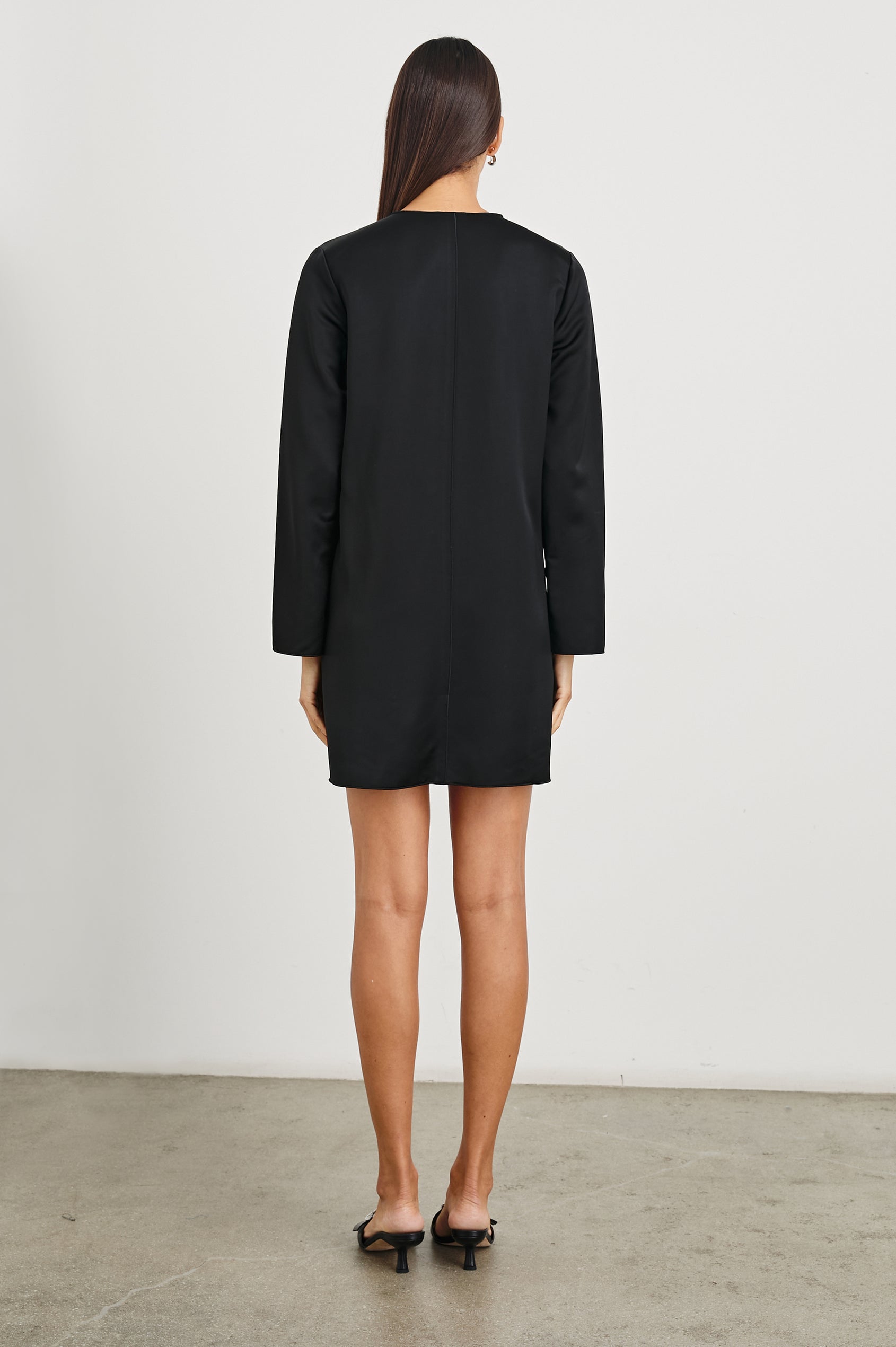 Victoria Long-Sleeve Mini Dress with a V Neck, and Front and Back Center Vertical Seams in Black Colorway - Back Full Body View Featured on Model 