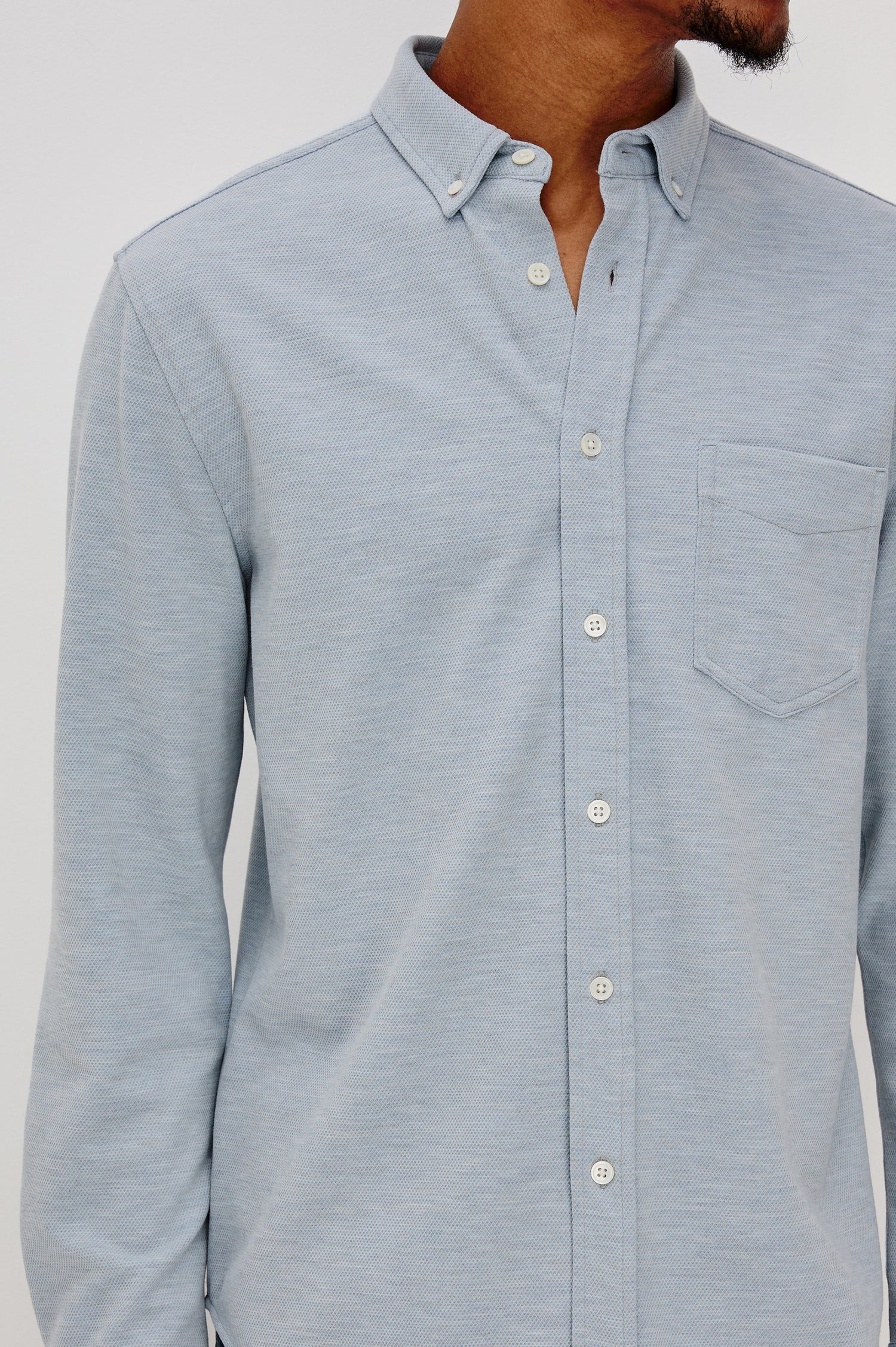 Vincent is a collared long sleeve button front shirt with a chest pocket in Blue Oxford colorway. Front detail view featured on model.