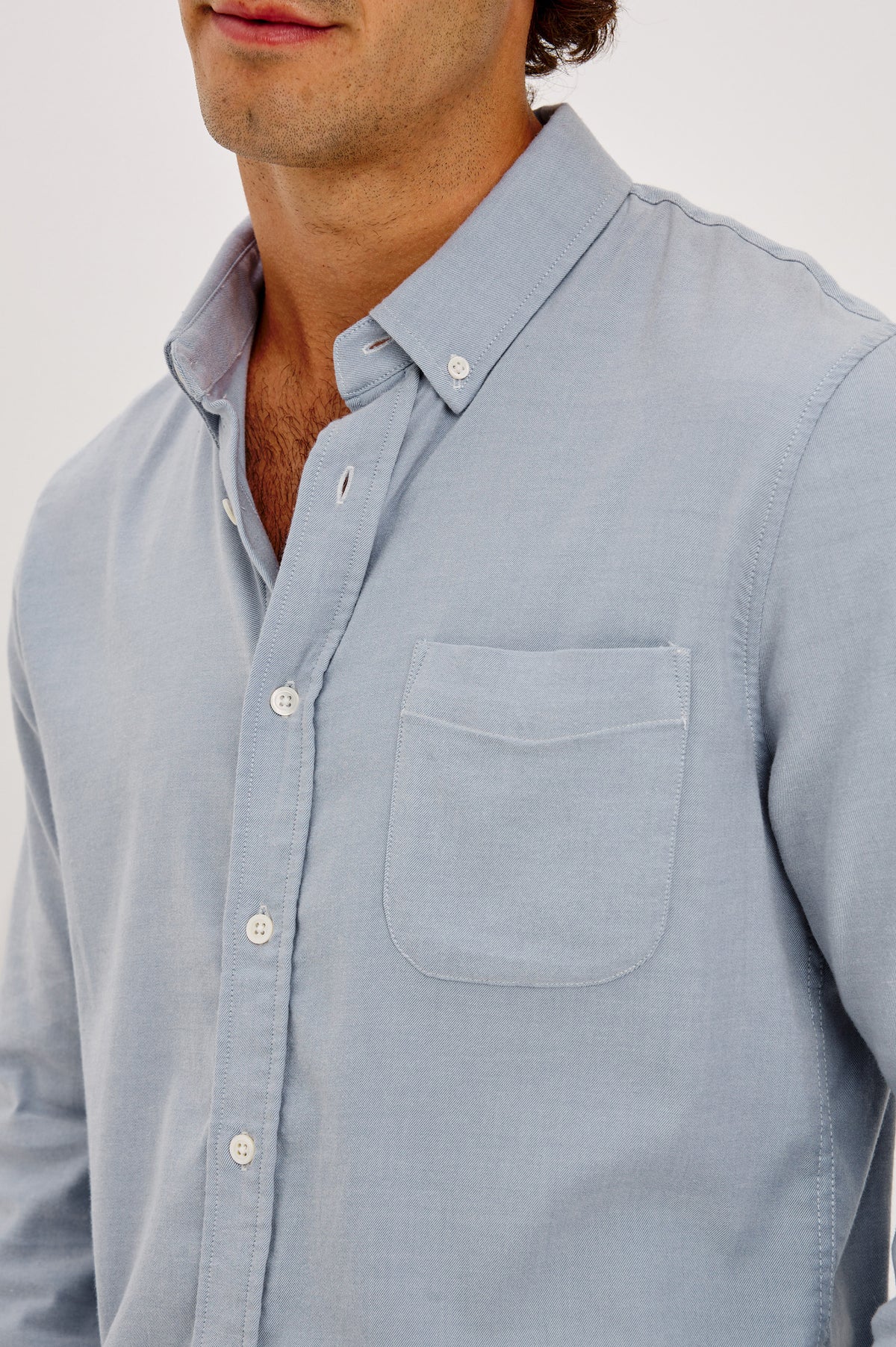 Vincent is a Collared Long Sleeve Button Front Shirt with a Chest Pocket in Blue Oxford Colorway - Upper Body Front Detail View Featured on Model.