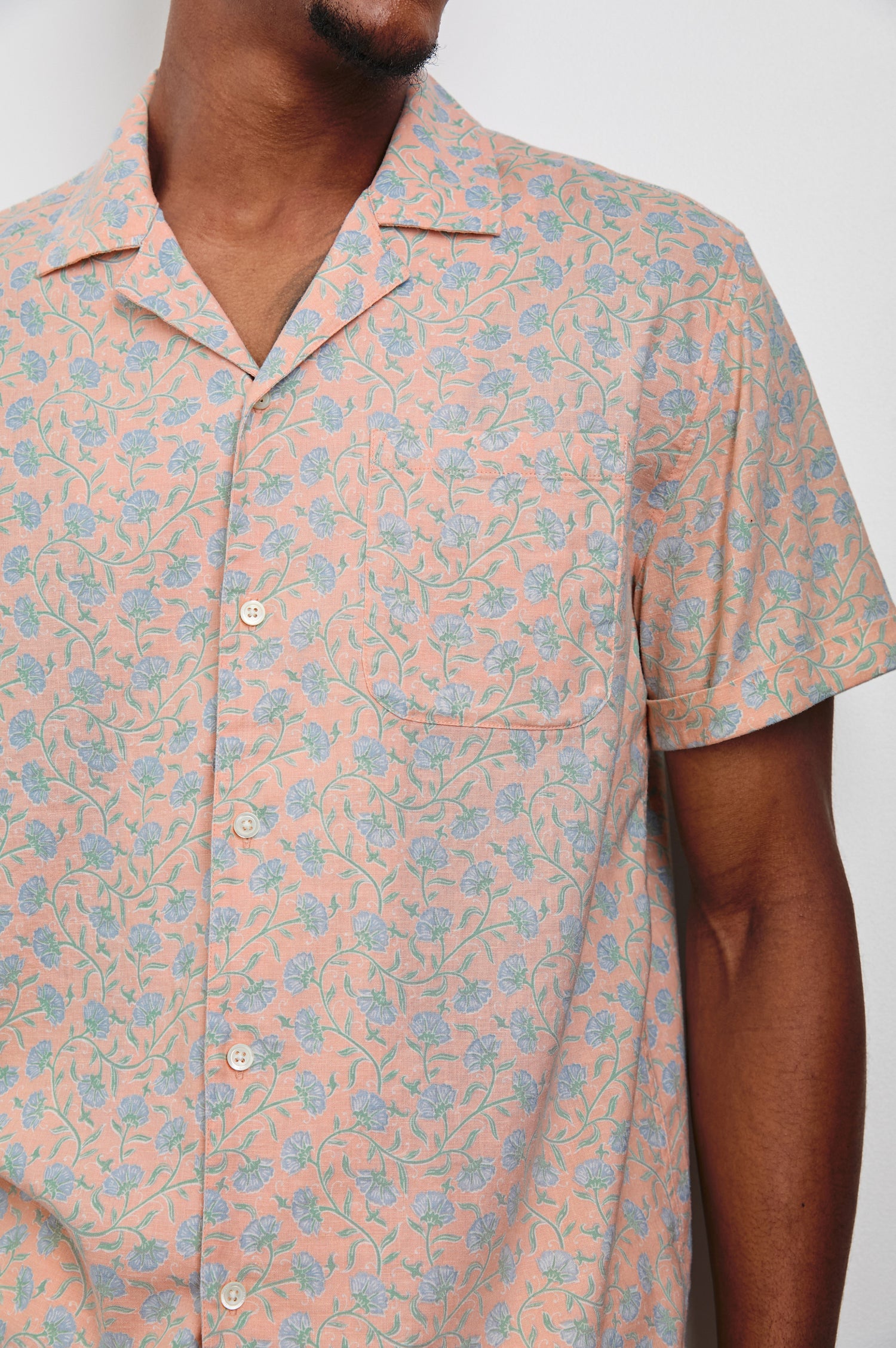 Waimea Short-Sleeve Button Up with a Chest Patch Pocket in Floral Batik Blossom Colorway, blue flowers on peach - Front View Featured on Model