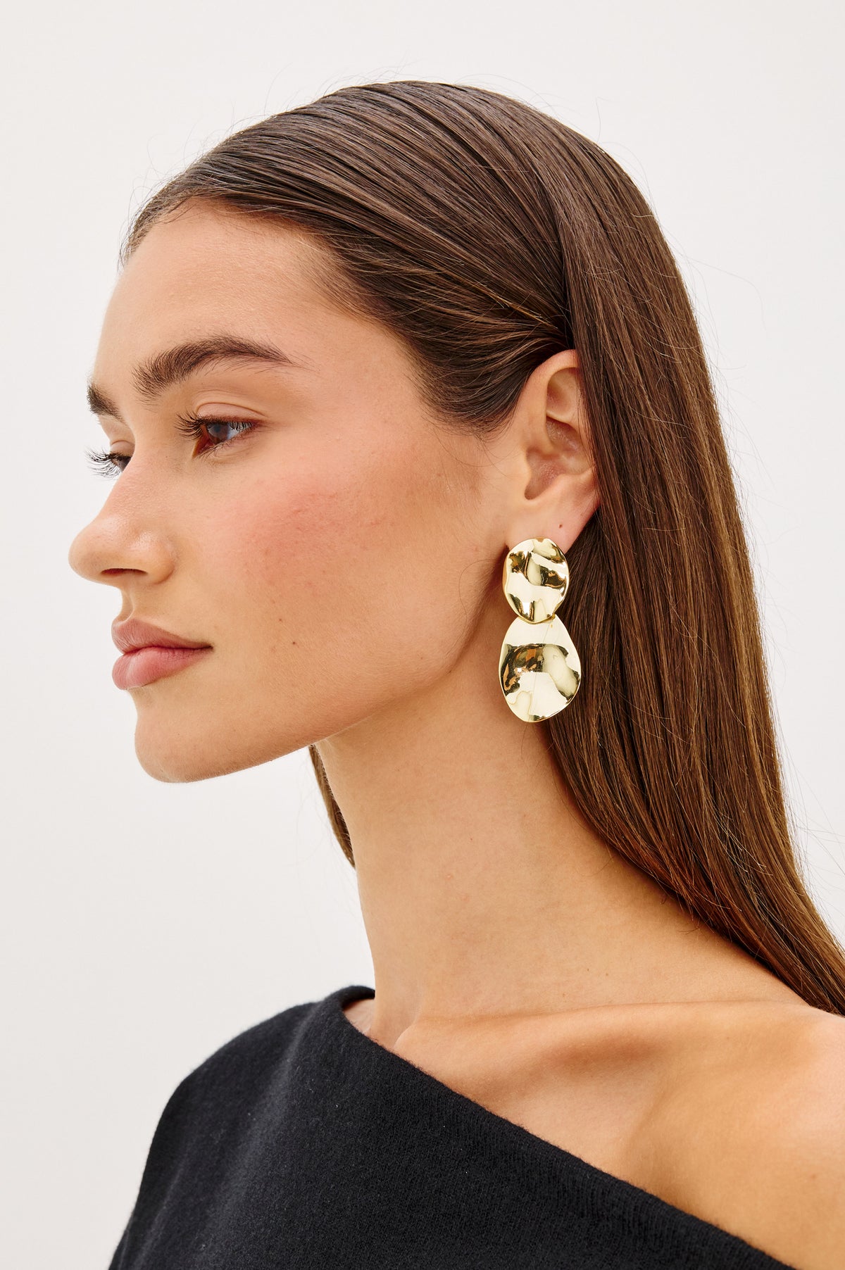 Wavy Drop Earrings With Engraved Rails Logo and Post Back Closure in Gold Colorway - Side view of product featured on model.