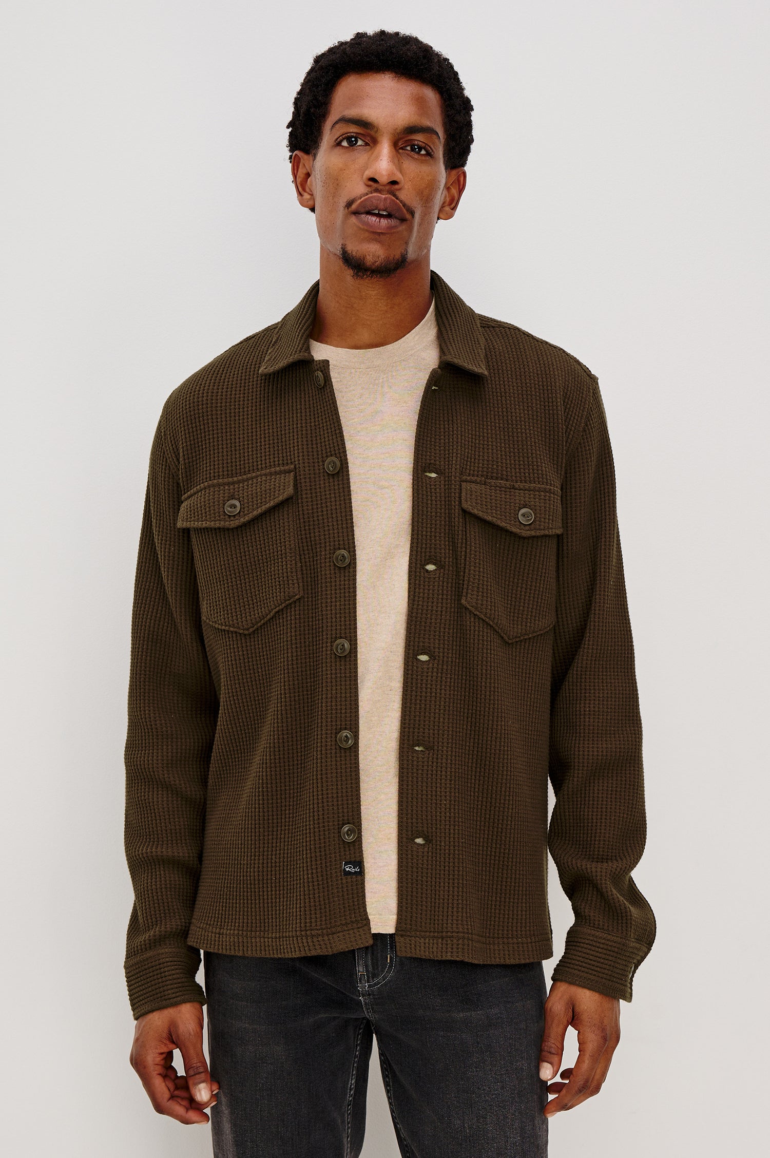 The Wells is a collared button front shirt jacket with contrast brown buttons and two chest pockets in Barley colorway. Front view featured on model.