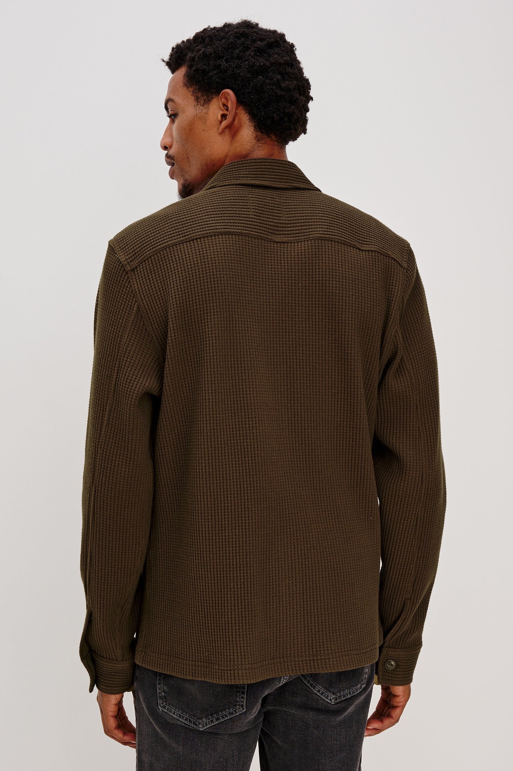 The Wells is a collared button front shirt jacket with contrast brown buttons and two chest pockets in Barley colorway. Back view featured on model.
