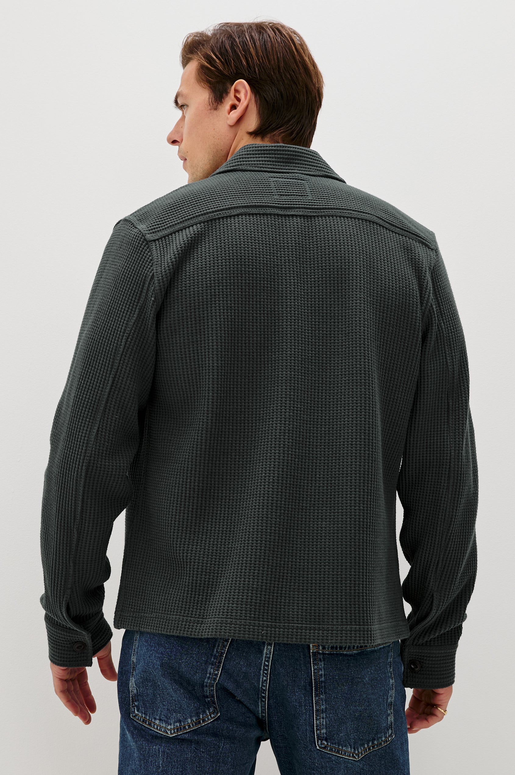 The Wells is a collared button front shirt jacket with contrast brown buttons and two chest pockets in Ink colorway. Back view featured on model.