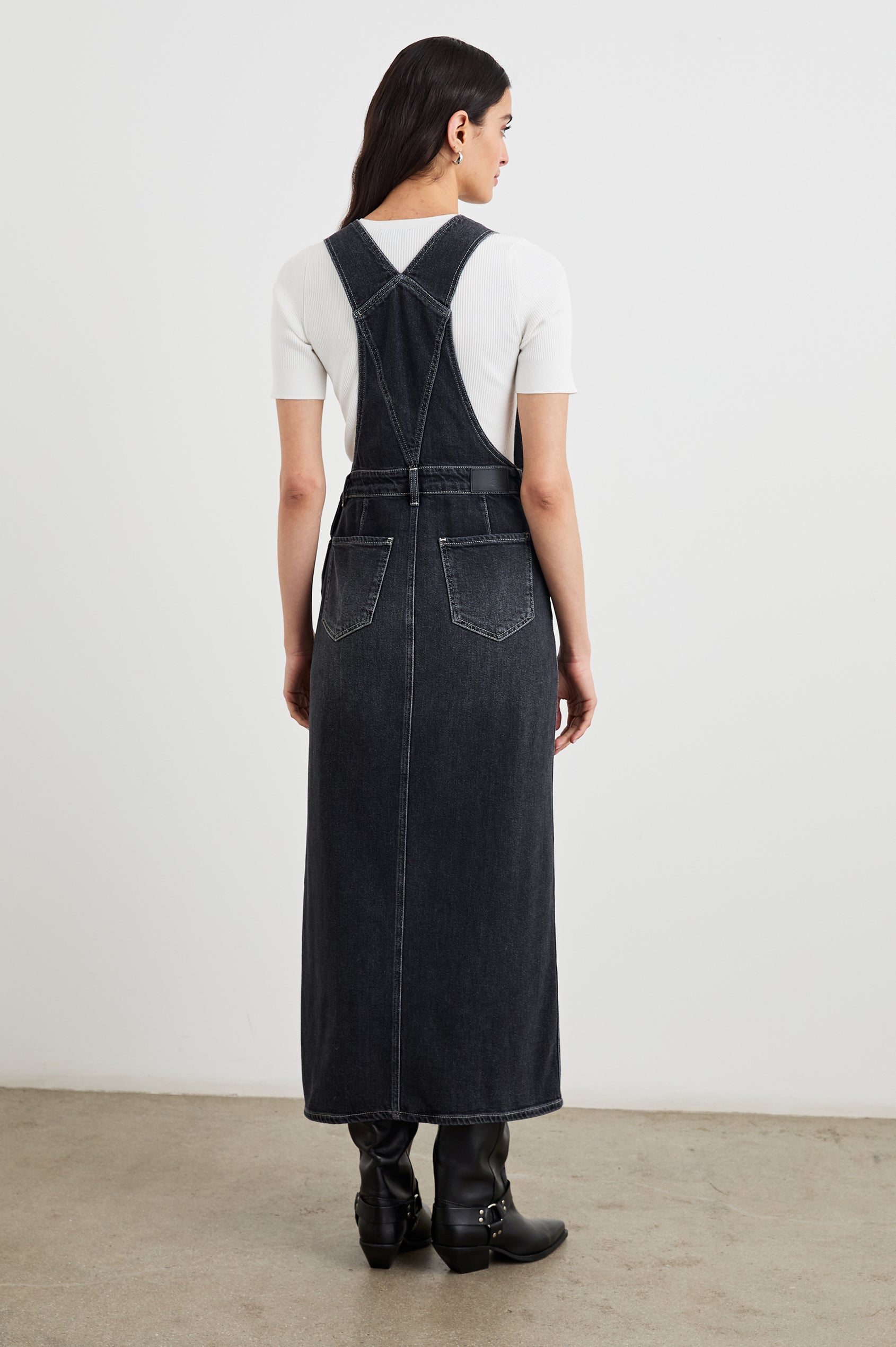 Westlake Midi Denim Dress with an Overalls-Style Bodice, Two Front Pockets, a Bib Chest Patch Pocket, Two Back Patch Pockets, Belt Loops and a Center Slit in Black Sand Colorway - Back Full Body View Featured on Model