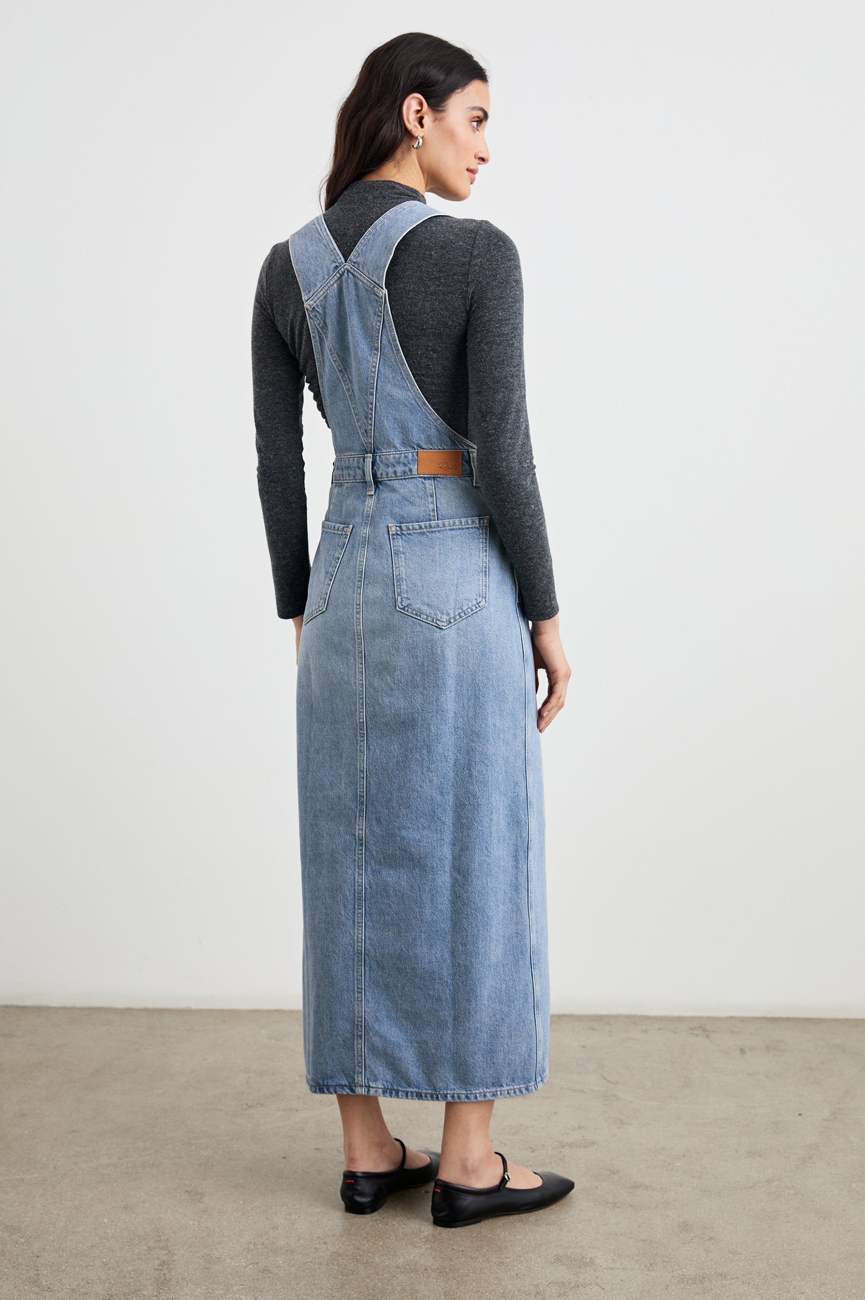 Westlake Midi Denim Dress with an Overalls-Style Bodice, Two Front Pockets, a Bib Chest Patch Pocket, Two Back Patch Pockets, Belt Loops and a Center Slit in South Coast Colorway - Back Full Body View Featured on Model
