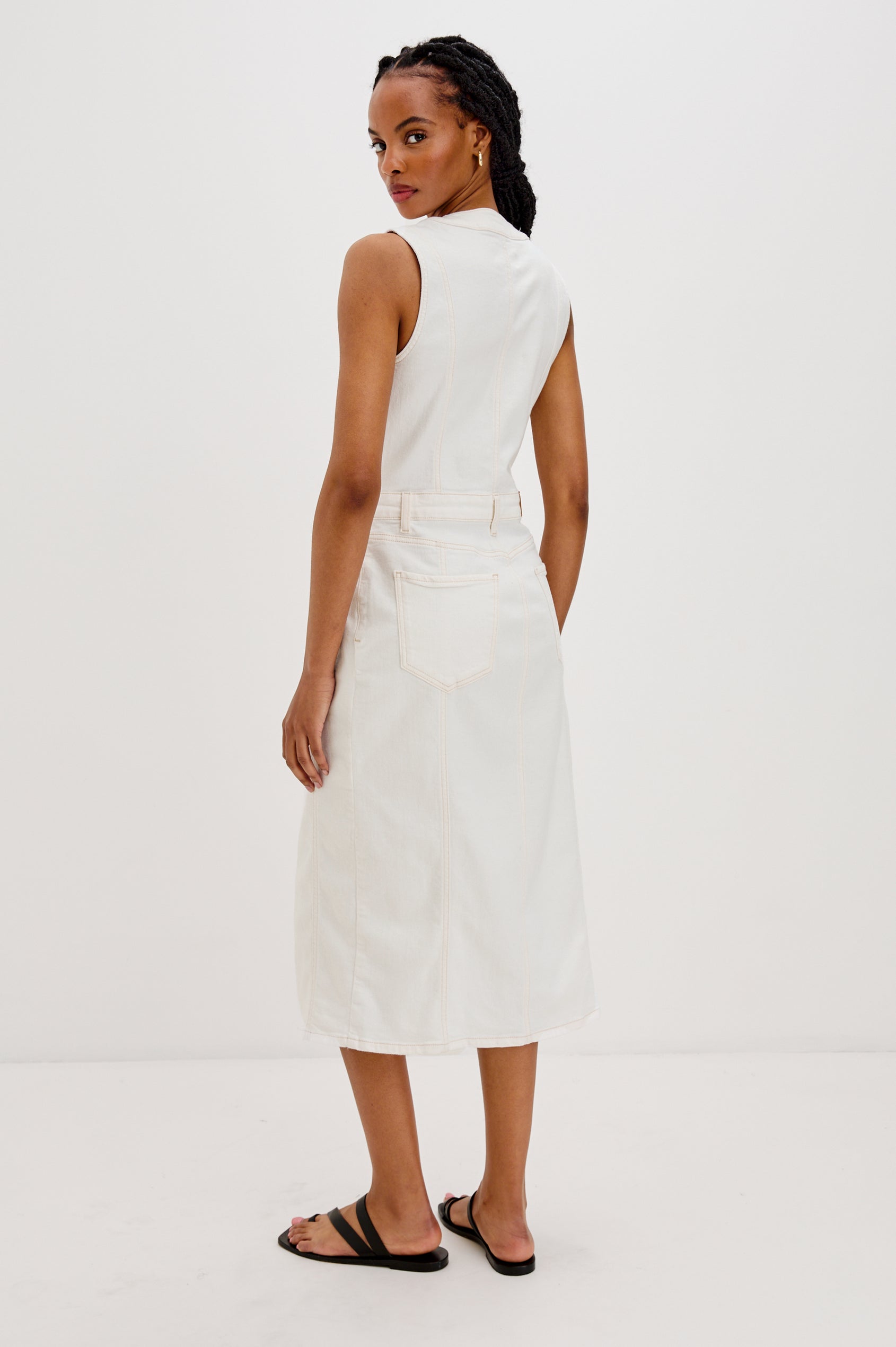 Westwood Sleeveless Denim Midi Dress with Belt Loops, a Button and Zipper Closure for the Skirt and Button Closure on the Bodice, a V neck, a Front Center Thigh Slit, Two Front Pockets  and Two Back Patch Pockets in Vintage Ecru Colorway - back view on model