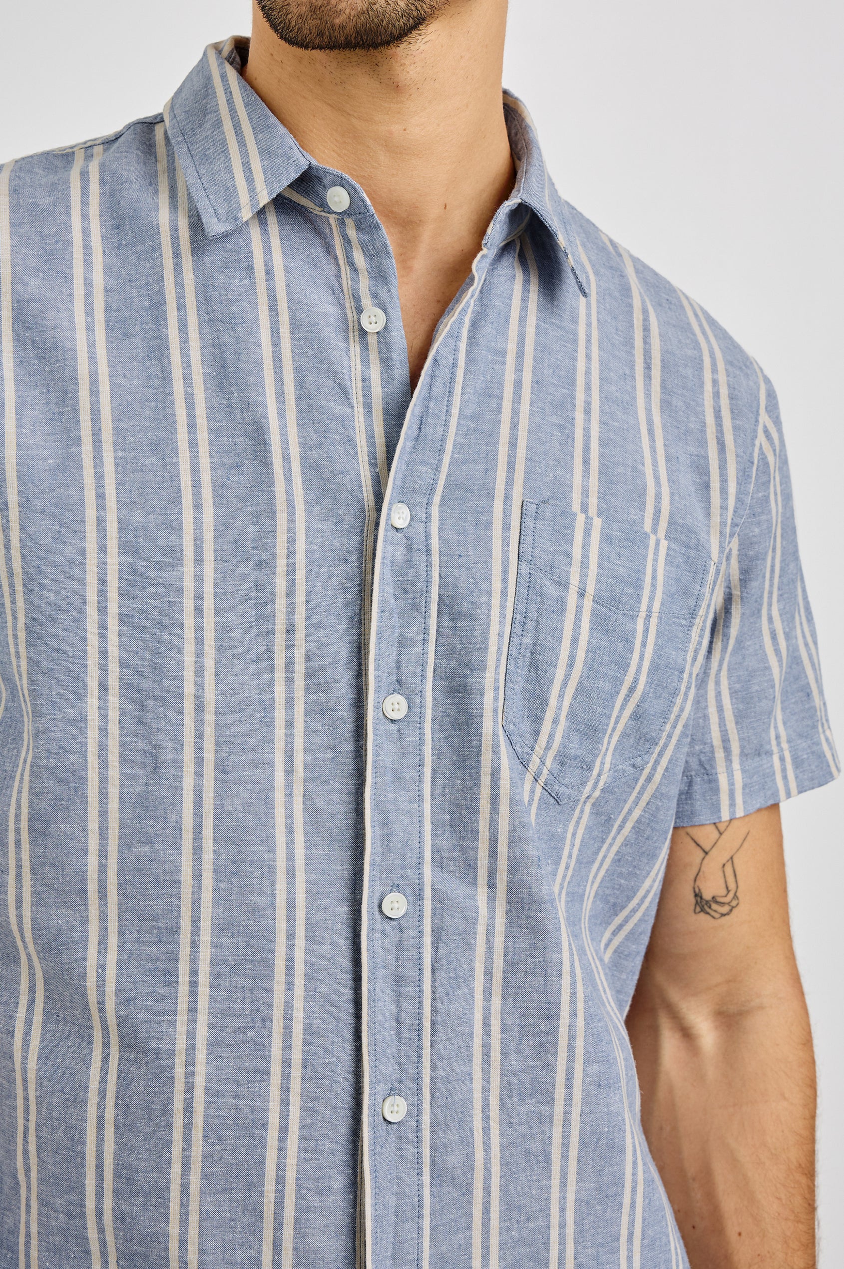 Wilder Collared Button Front Shirt with Short Sleeves and a Chest Pocket in Chambray Butter Colorway. Front Detail View Shown on Model.