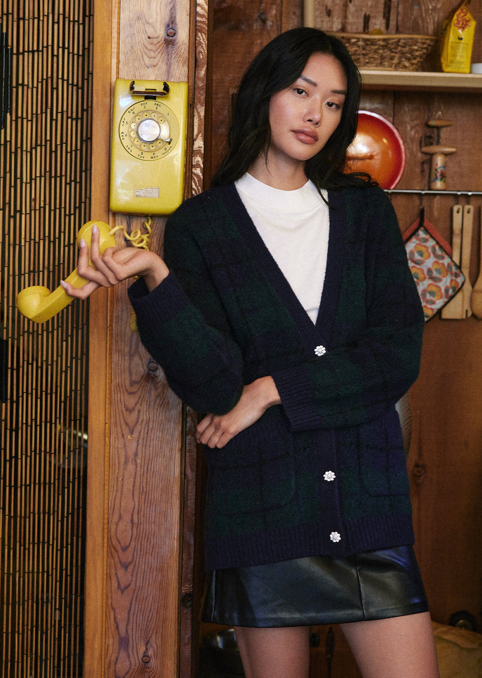 FRONT EDITORIAL IMAGE OF MODEL WEARING RUNI CARDIGAN IN NAVY TARTAN AND PRIM SKIRT IN BLACK