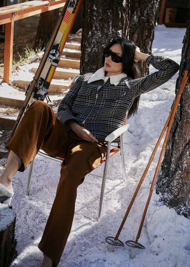 EDITORIAL SHOT OF MODEL SITTING DOWN WEARING CHEYENNE JACKET IN ONYX TAUPE PINK AND HARLOW PANT IN HENNA