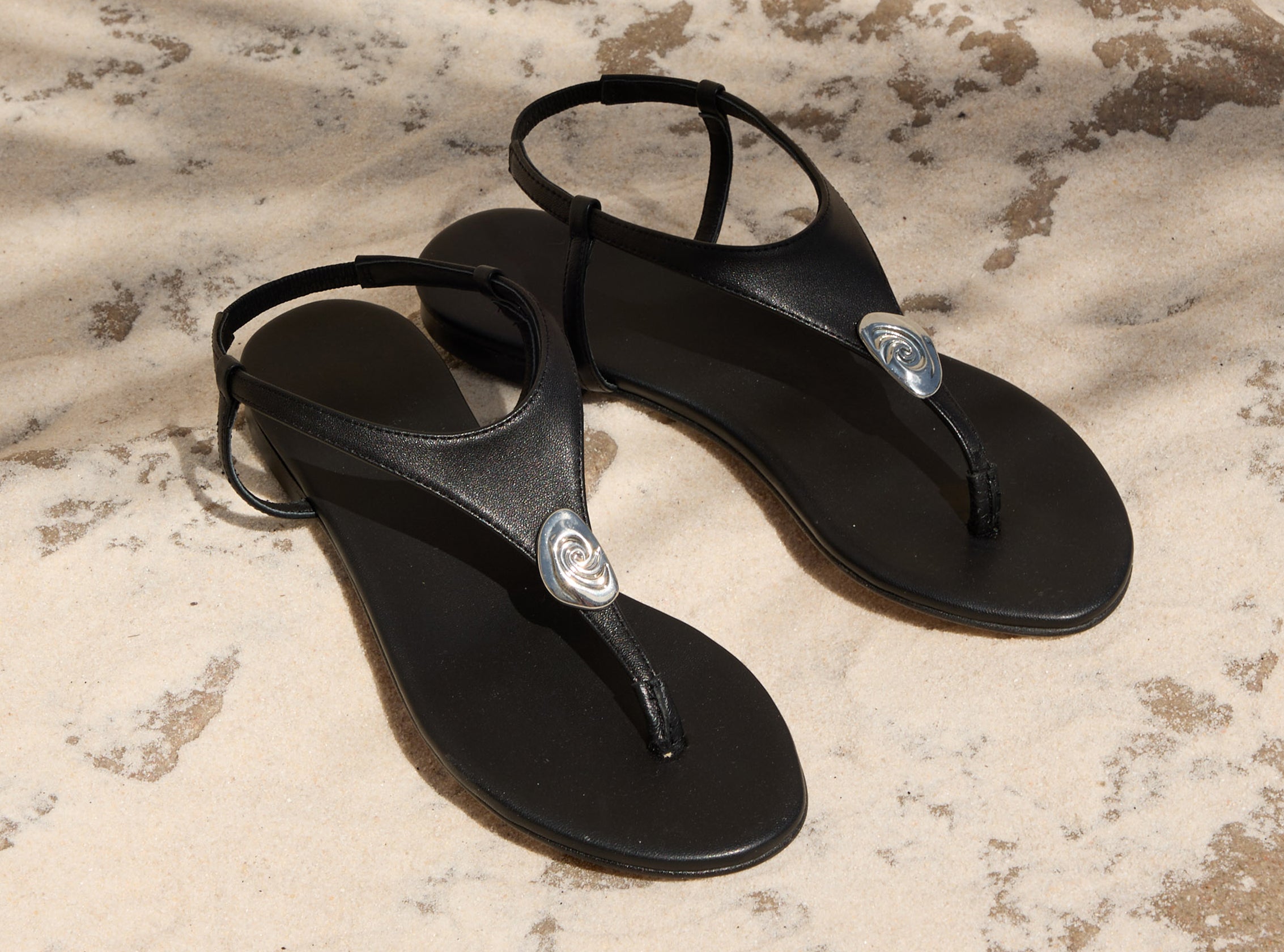 Black sandals with a brand logo on a textured surface