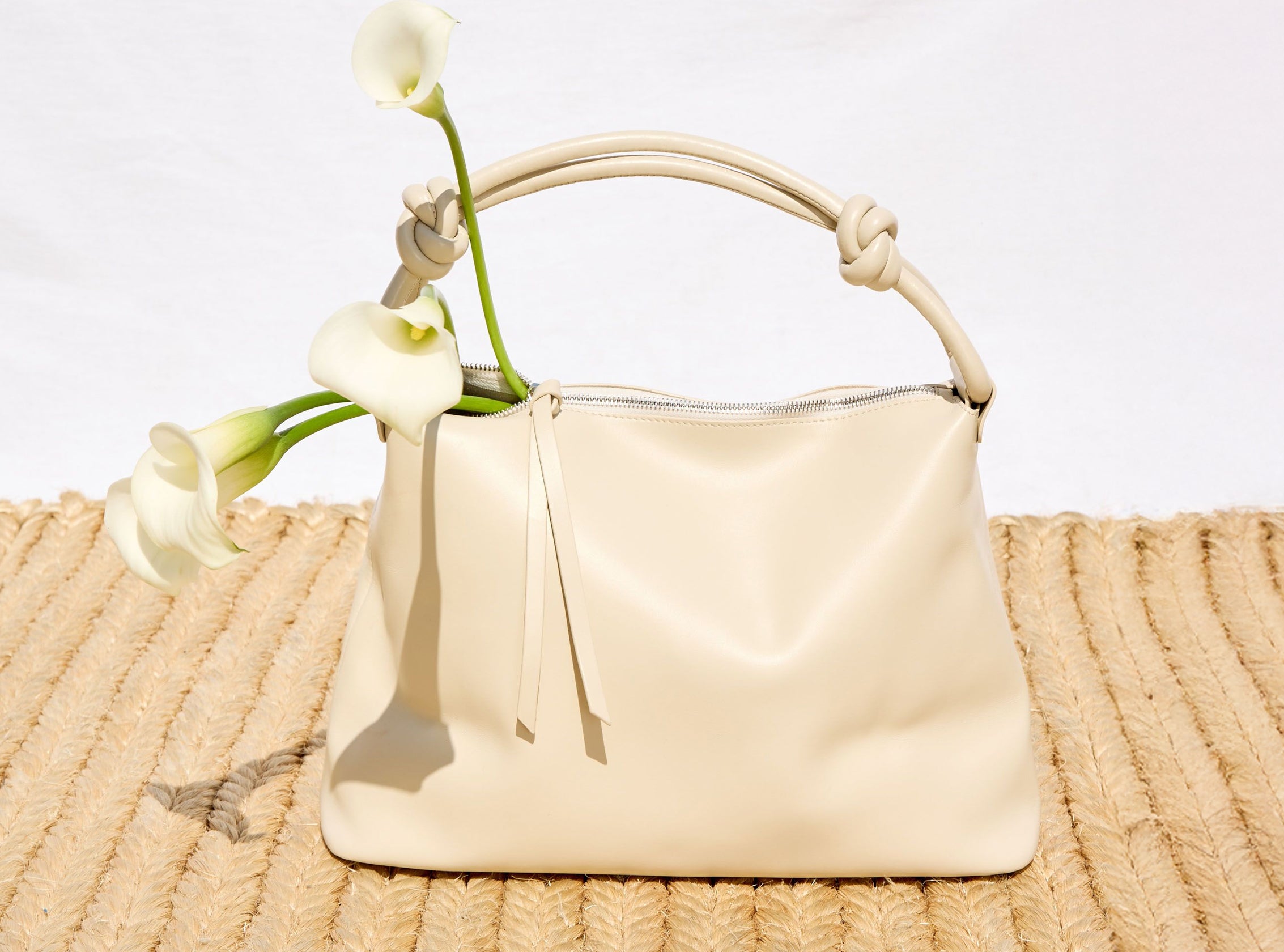 Beige handbag with white flowers on a textured surface