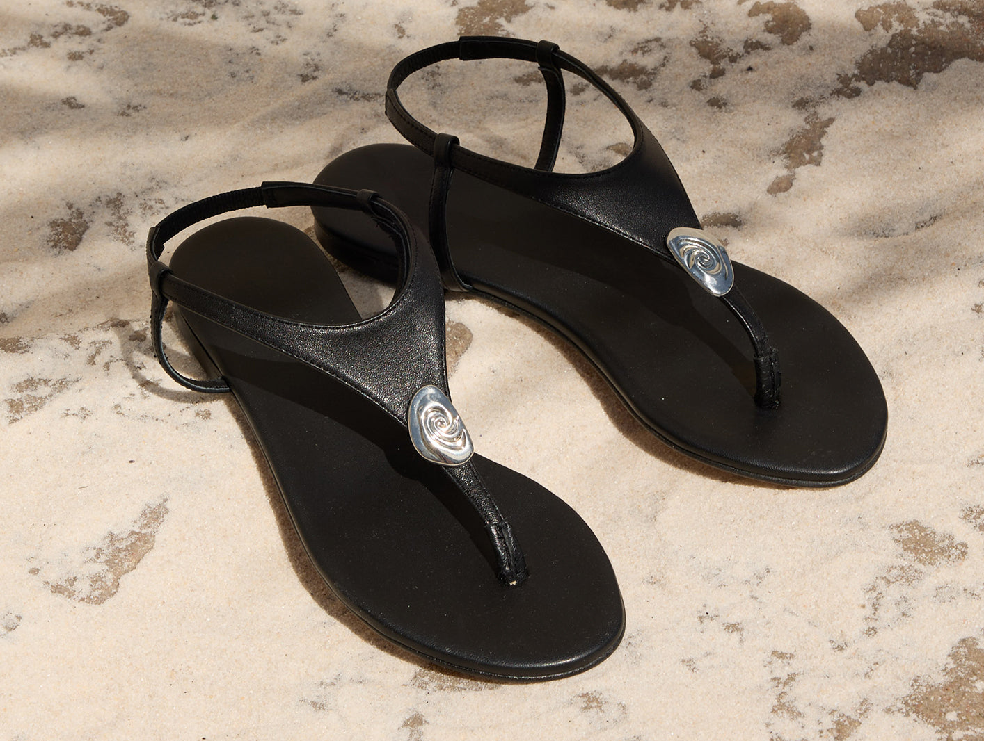 Black sandals with a brand logo on a textured surface