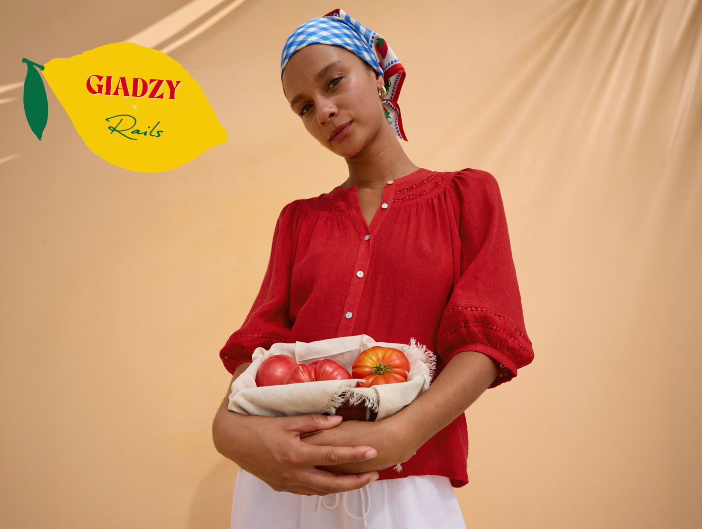 Woman wearing a red top with a gingham print head scarf while holding tomatoes