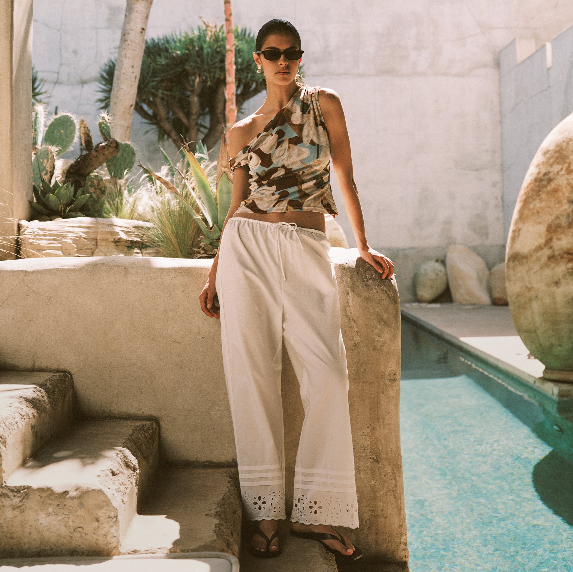 Woman wearing a colorful floral top with white embroidered pants 