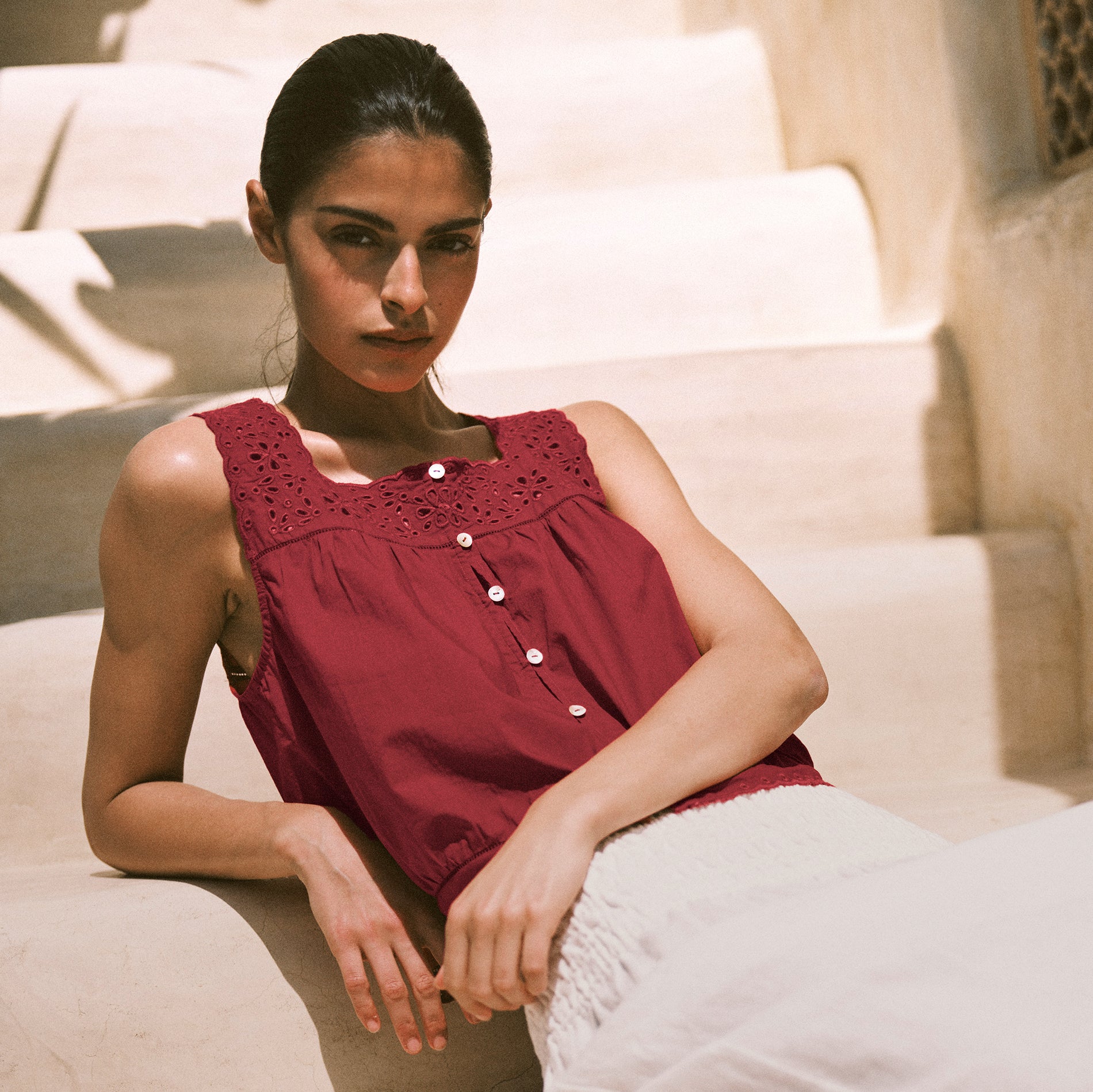 Woman wearing a red sleeveless top sitting on a staircase.