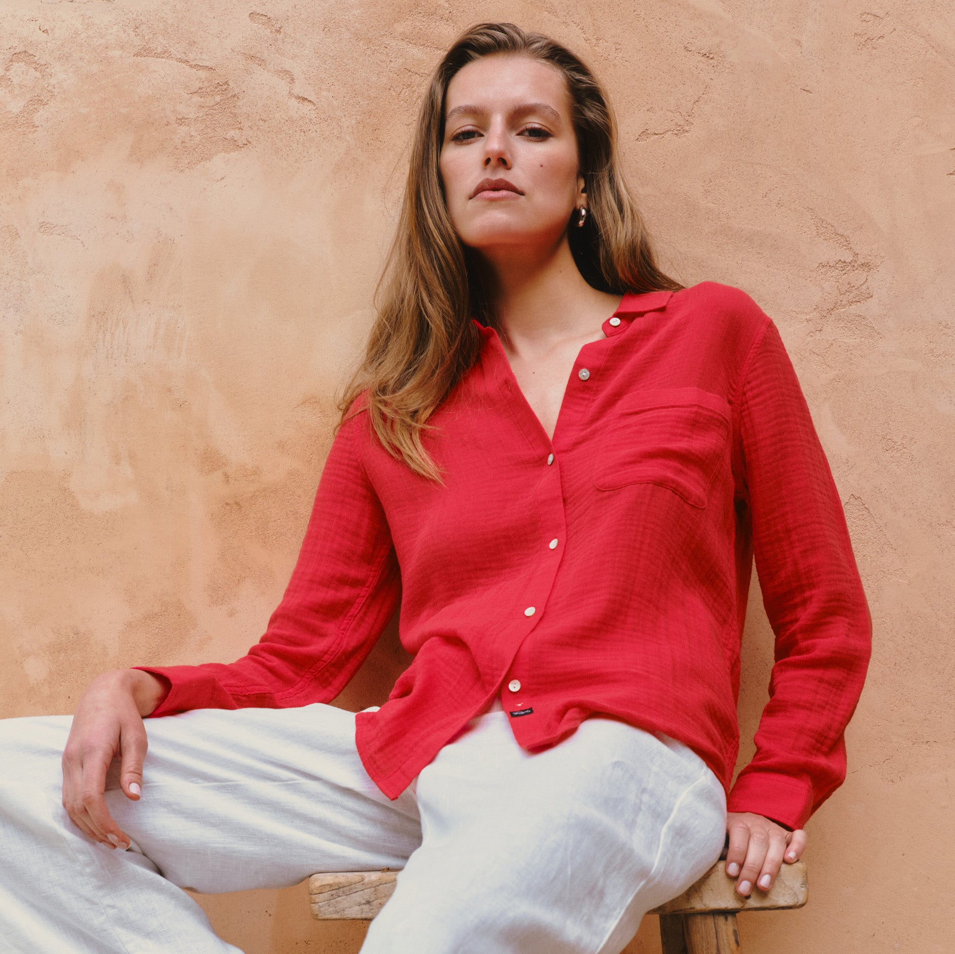 Woman wearing a red button-down shirt with white pants