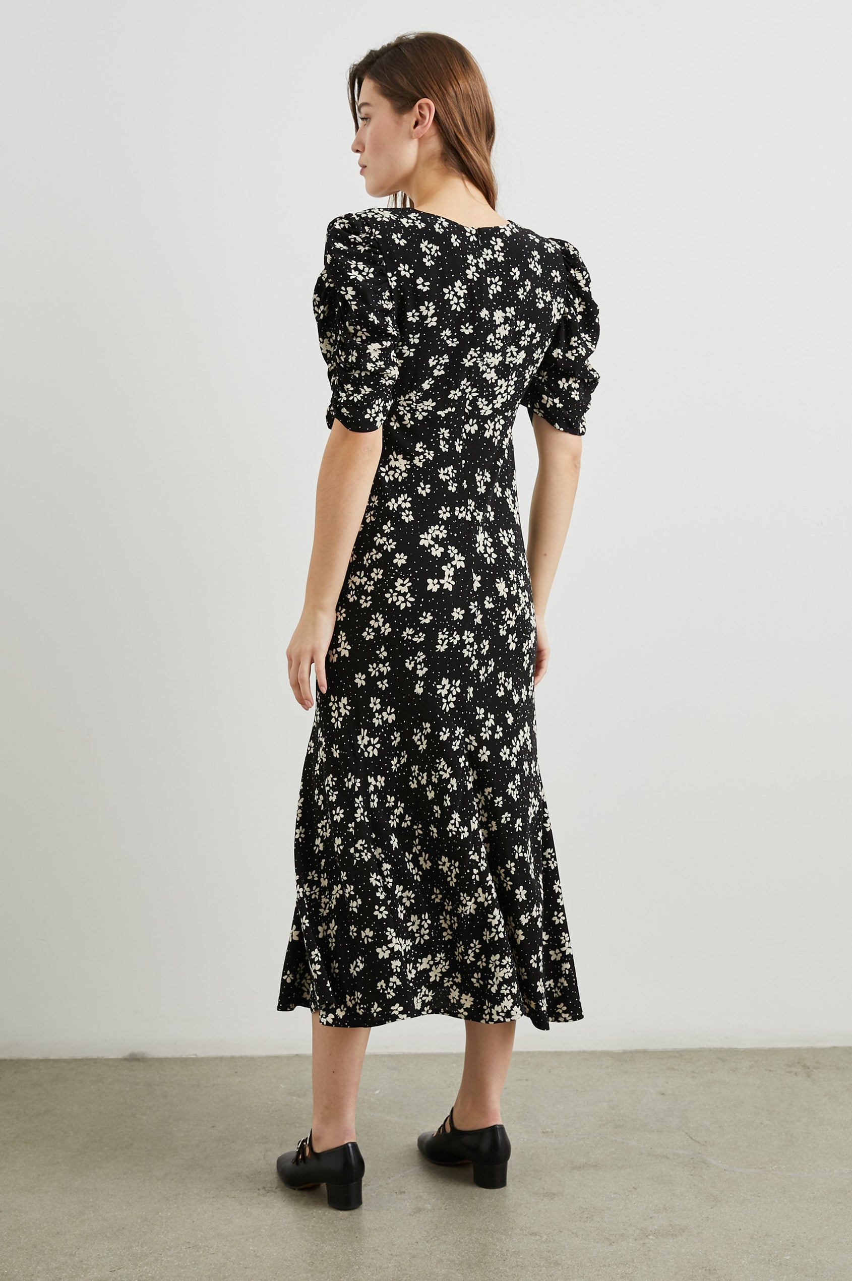 Zariah Midi Dress with Mid-Length Sleeves with Light Ruching, a Deep V Neck and an Empire Waist in Noir Floral Colorway, with white flowers on black - Back Full Body View Featured on Model