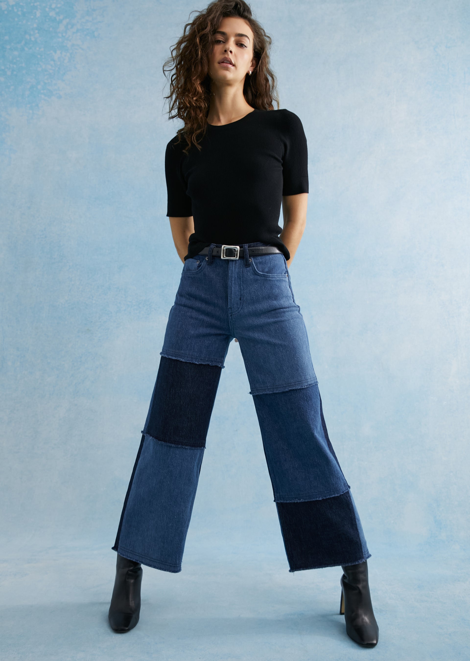 FRONT FULL BODY EDITORIAL IMAGE OF MODEL WEARING GETTY WIDE LEG JEANS IN BLUE PATCHWORK