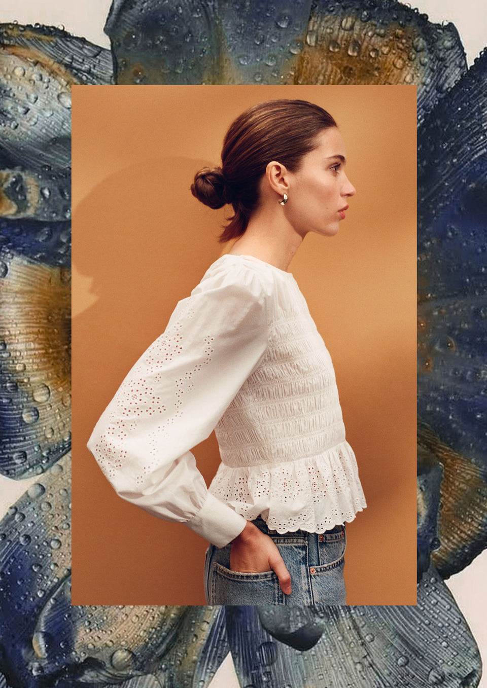 Woman wearing a white blouse and blue jeans against an orange background.