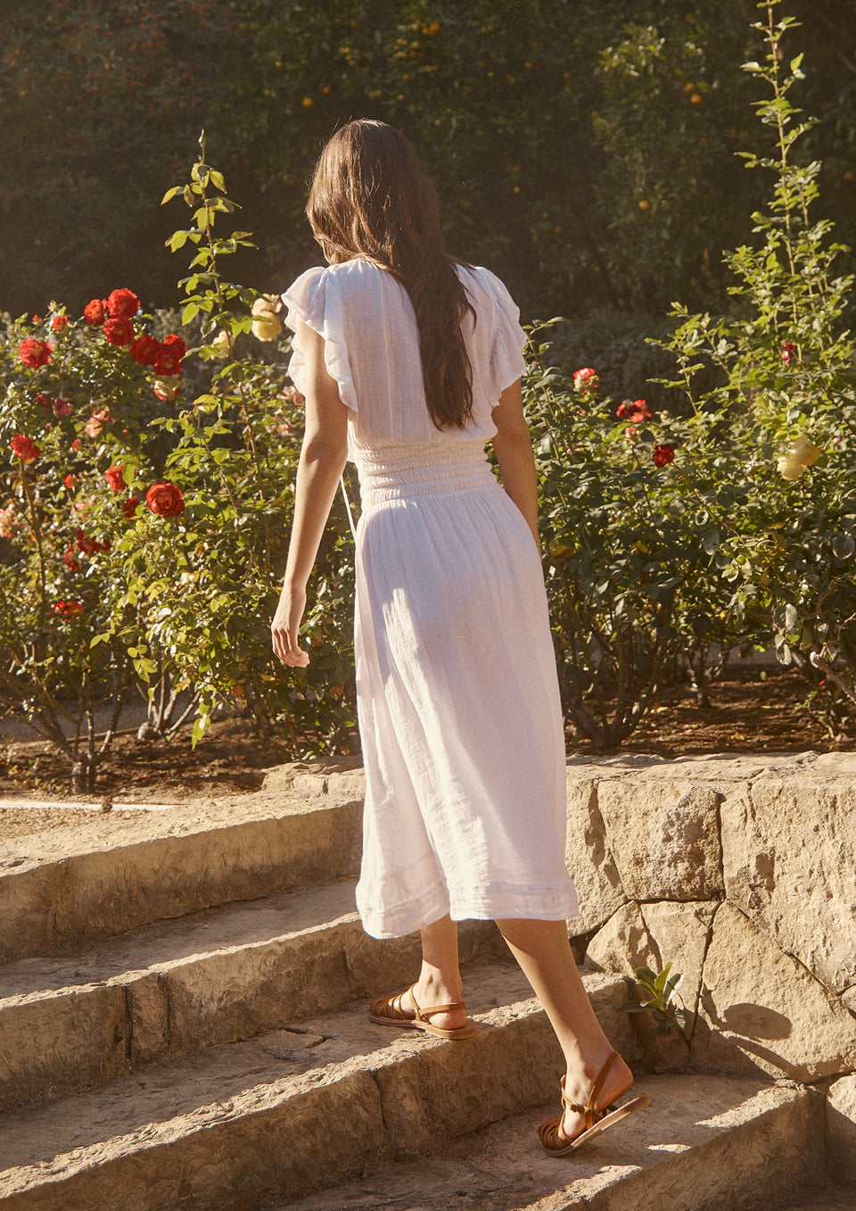 FULL BODY BACK SHOT OF MODEL IN GARDEN WEARING IONA DRESS