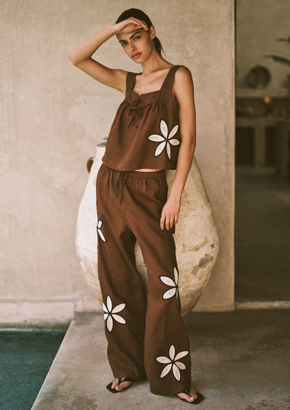 Woman wearing a brown set with white floral detailing on it