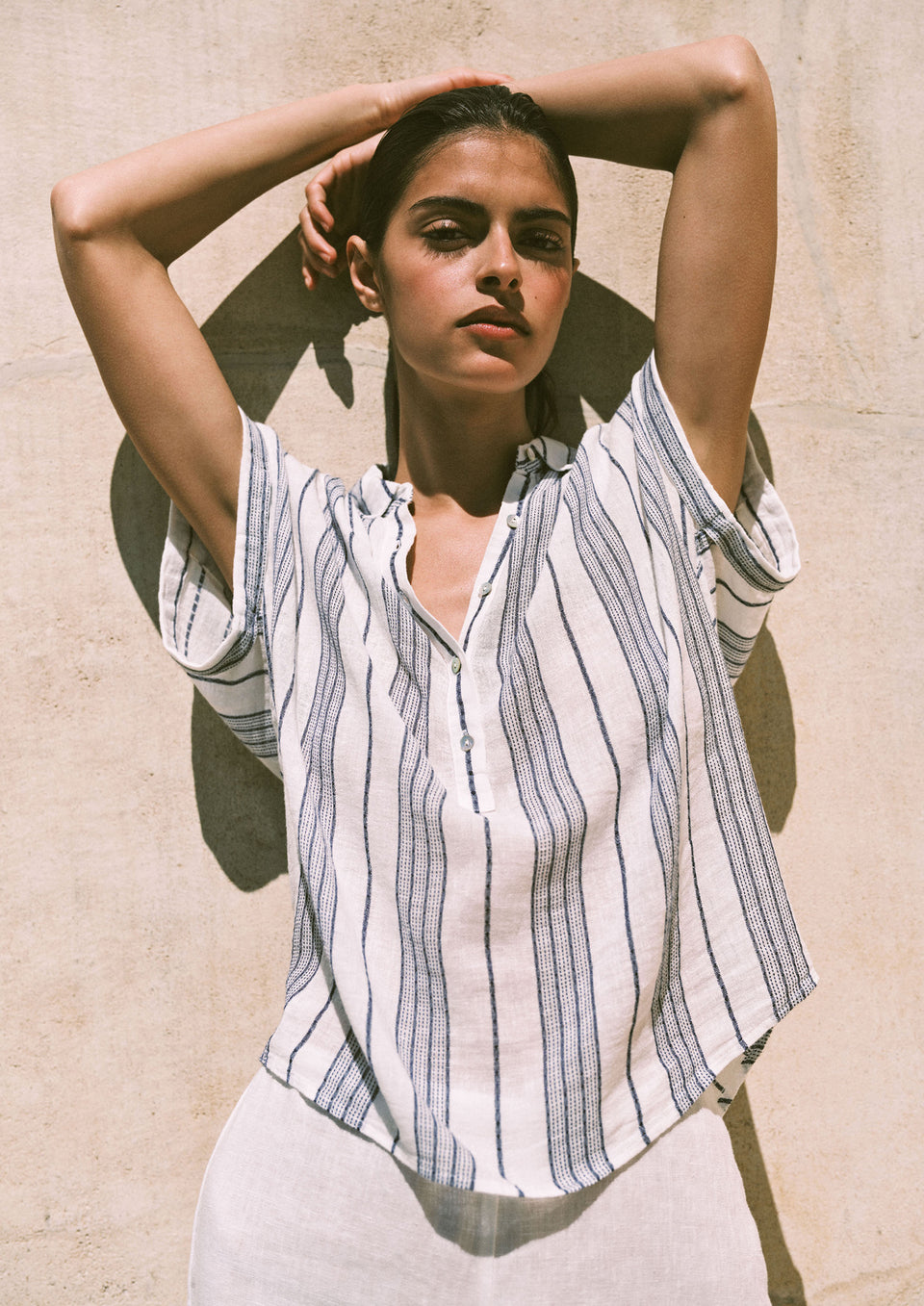 Woman wearing a striped shirt against a beige wall