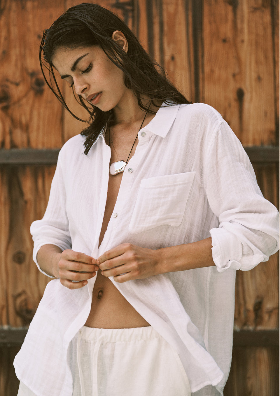 Woman wearing a white shirt and shorts against a wooden background