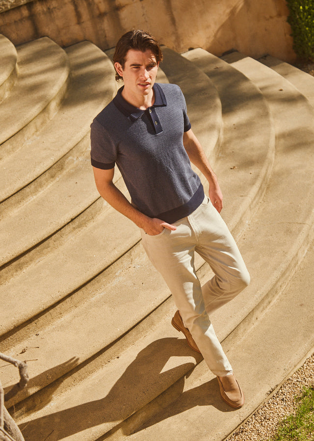 FRONT FULL BODY IMAGE OF MODEL WEARING SHOREDITCH POLO SHIRT IN NAVY BROCADE AND CARVER PANT IN STONE