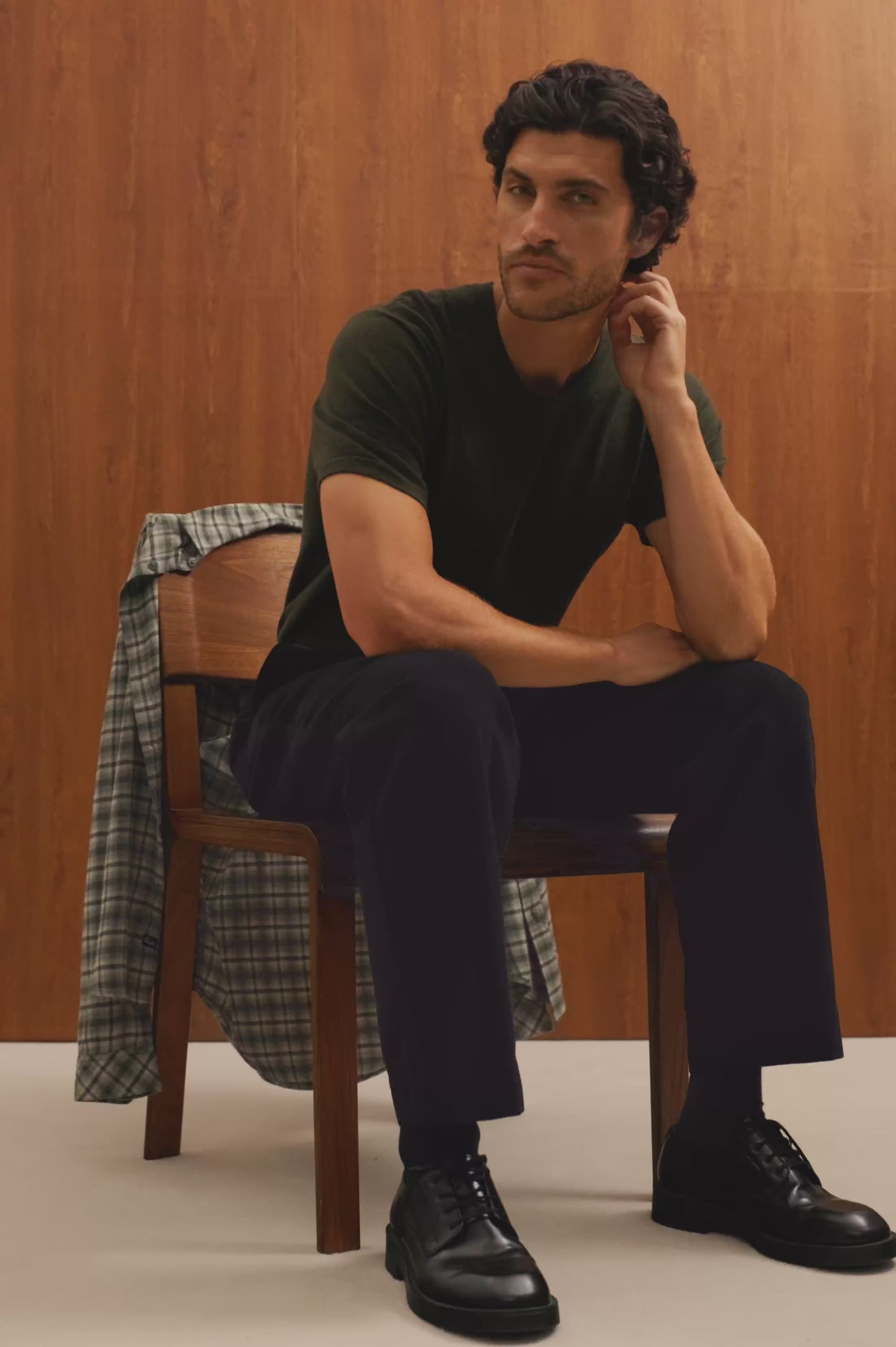 Ezra Pant in Brushed Cotton Twill With Relaxed Fit, Single Front Pleats, Ankle-Length Hem, Zip Fly, Side Pockets, and Back Double-Welt Pockets in Black Colorway - Video - Front View Featured on Sitting Model.