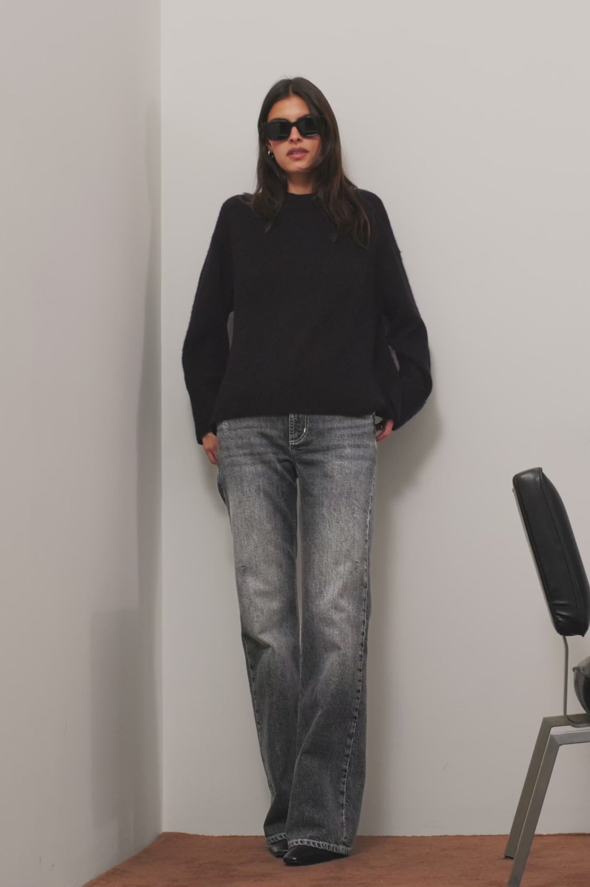 Alamitos Flared Trouser in Comfort Stretch Denim With High-Rise Relaxed Fit, Wide Legs, and 5-Pockets in Night Rider Colorway - Full Body View Featured on Model Posing with Chair (Video).