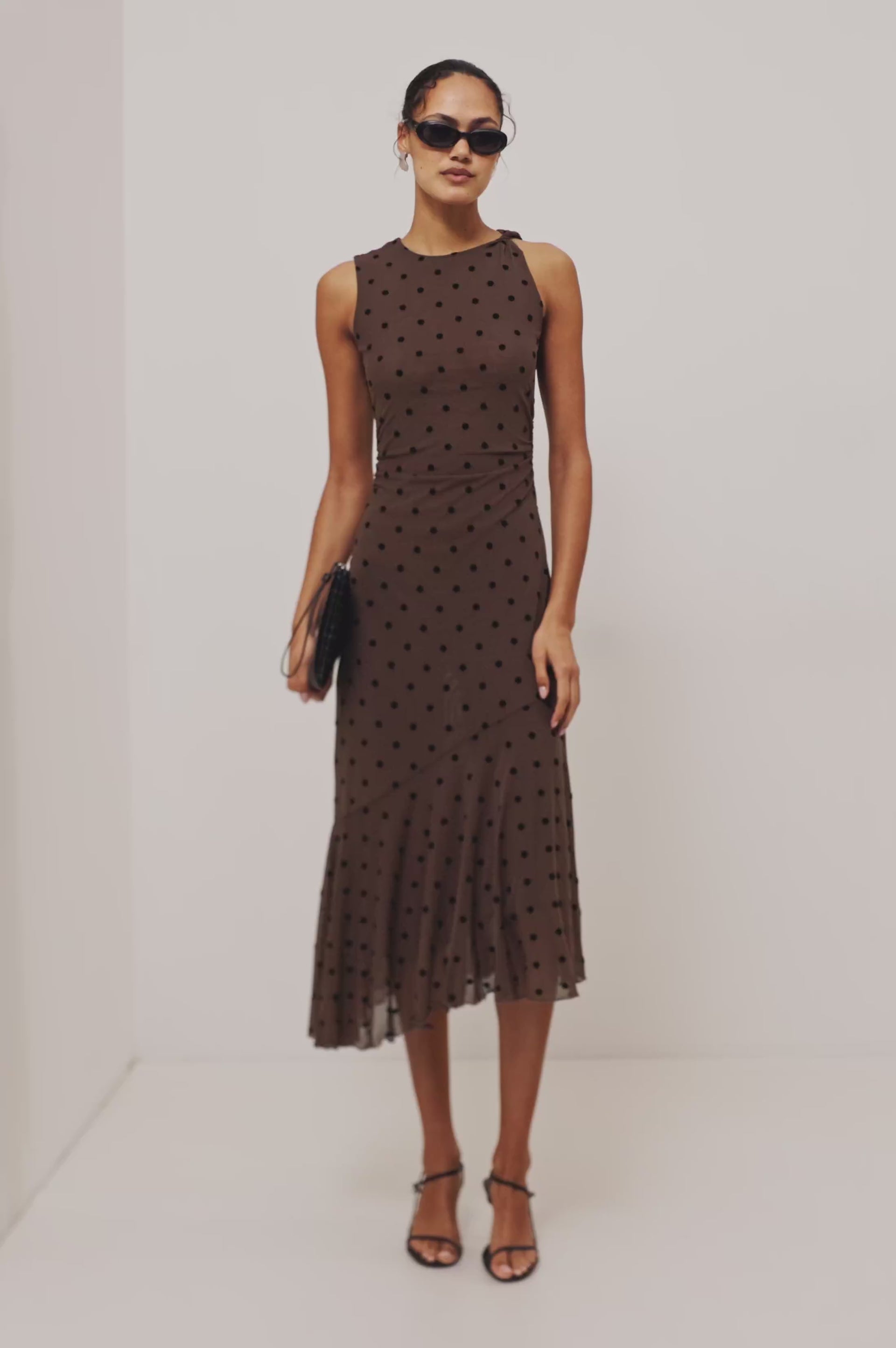 Daija Midi Dress in Self-Lined Mesh With High Neckline, Fitted Bodice, Side Waist Ruching, Bias Cut Skirt, and Asymmetric Hem in Chocolate Polka Dot Colorway - Full Body Front View Featured on Model - Video