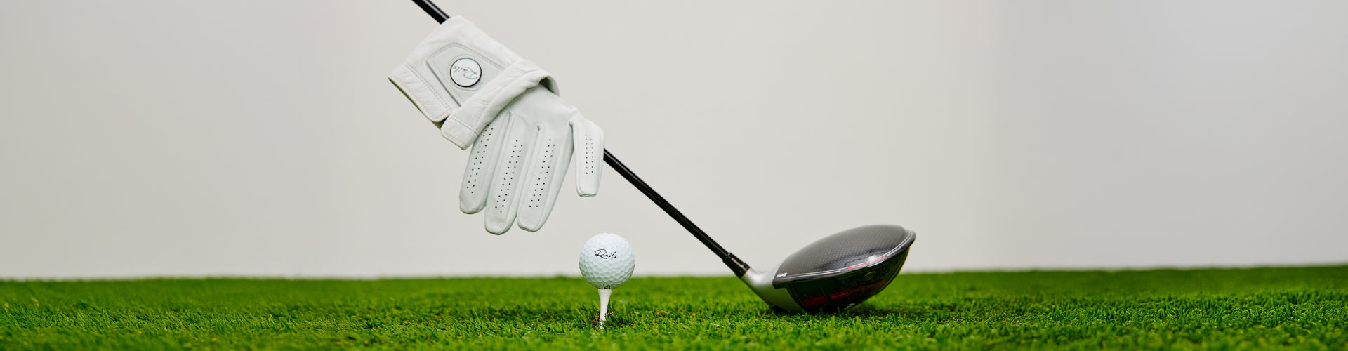 Golf club and glove on grass with a white background