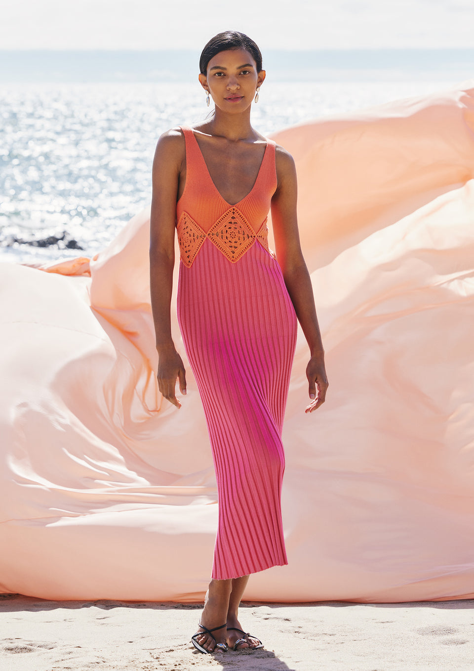 FRONT FULL BODY EDITORIAL IMAGE OF MODEL ON THE BEACH WEARING TARYN DRESS IN PAPAYA COLORBLOCK