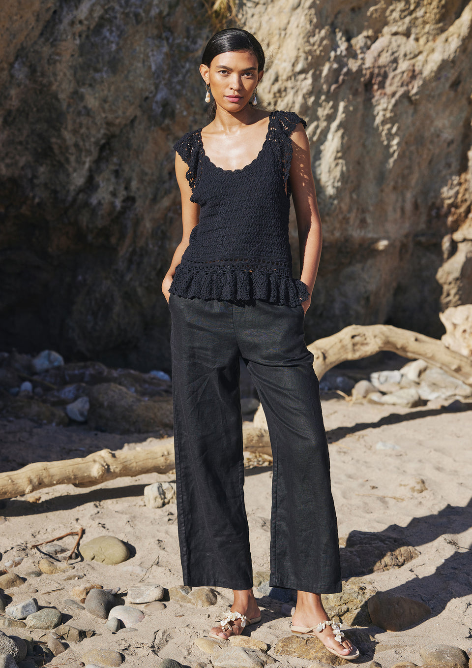 FRONT FULL BODY EDITORIAL IMAGE OF MODEL ON THE BEACH WEARING HATTIE TOP IN BLACK AND EMMIE PANT IN BLACK