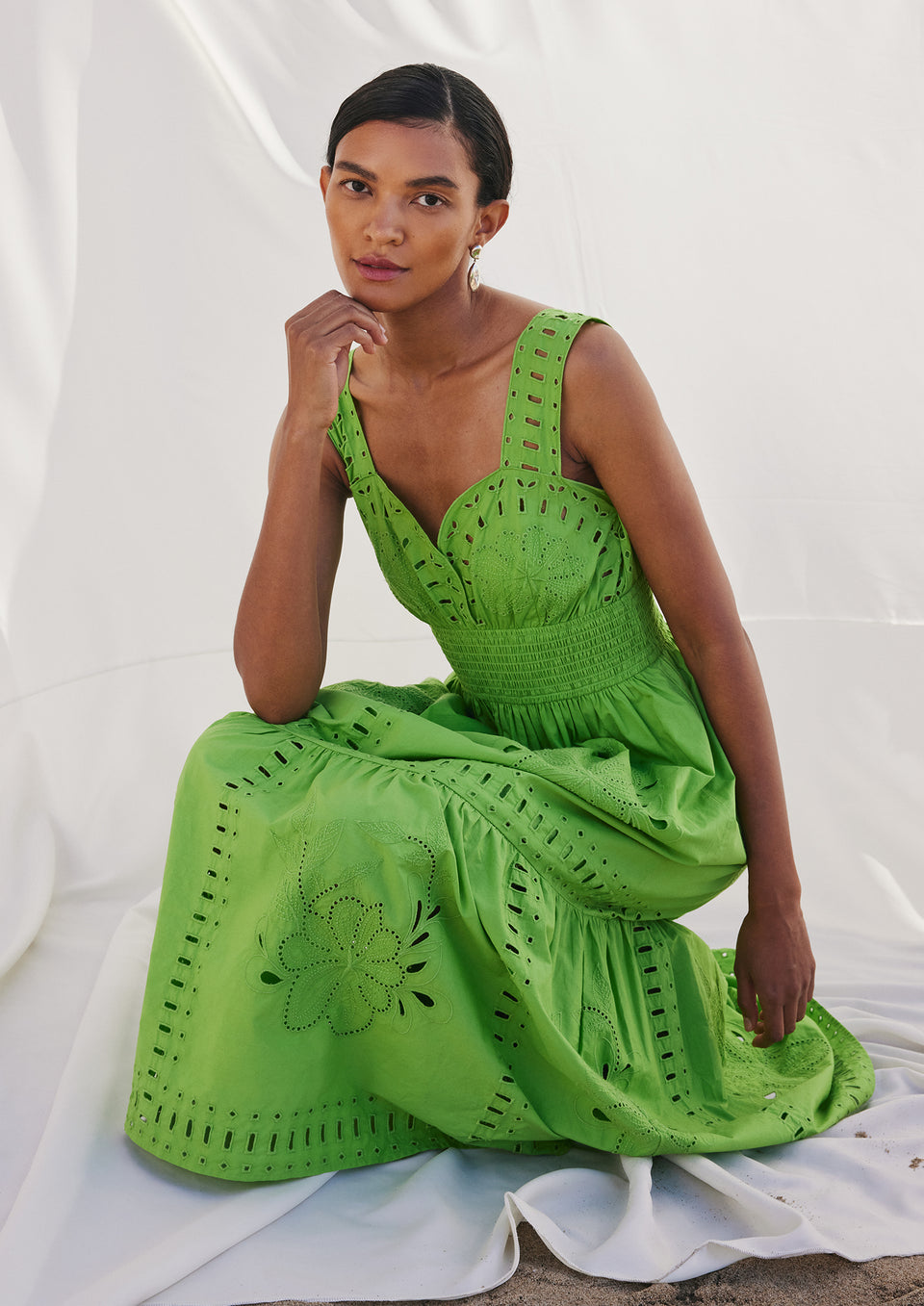 EDITORIAL IMAGE OF MODEL SITTING WEARING FAWN DRESS IN ISLAND GREEN