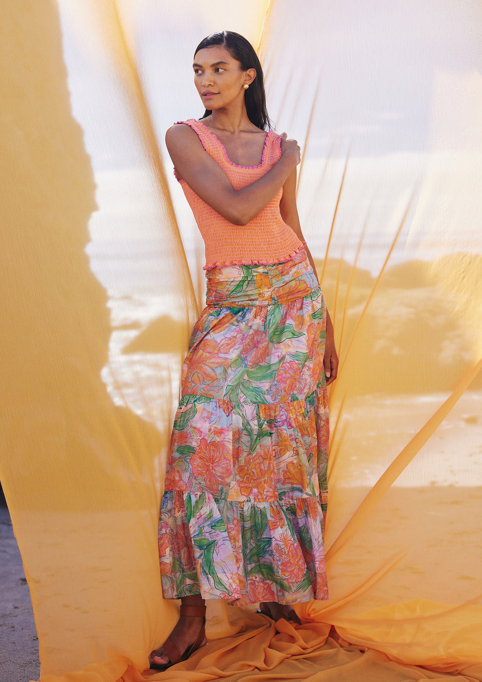 FRONT FULL BODY EDITORIAL IMAGE OF MODEL LOOKING TO THE SIDE WEARING MAXINE TOP IN PAPAYA AND AGATHA SKIRT IN TROPICS