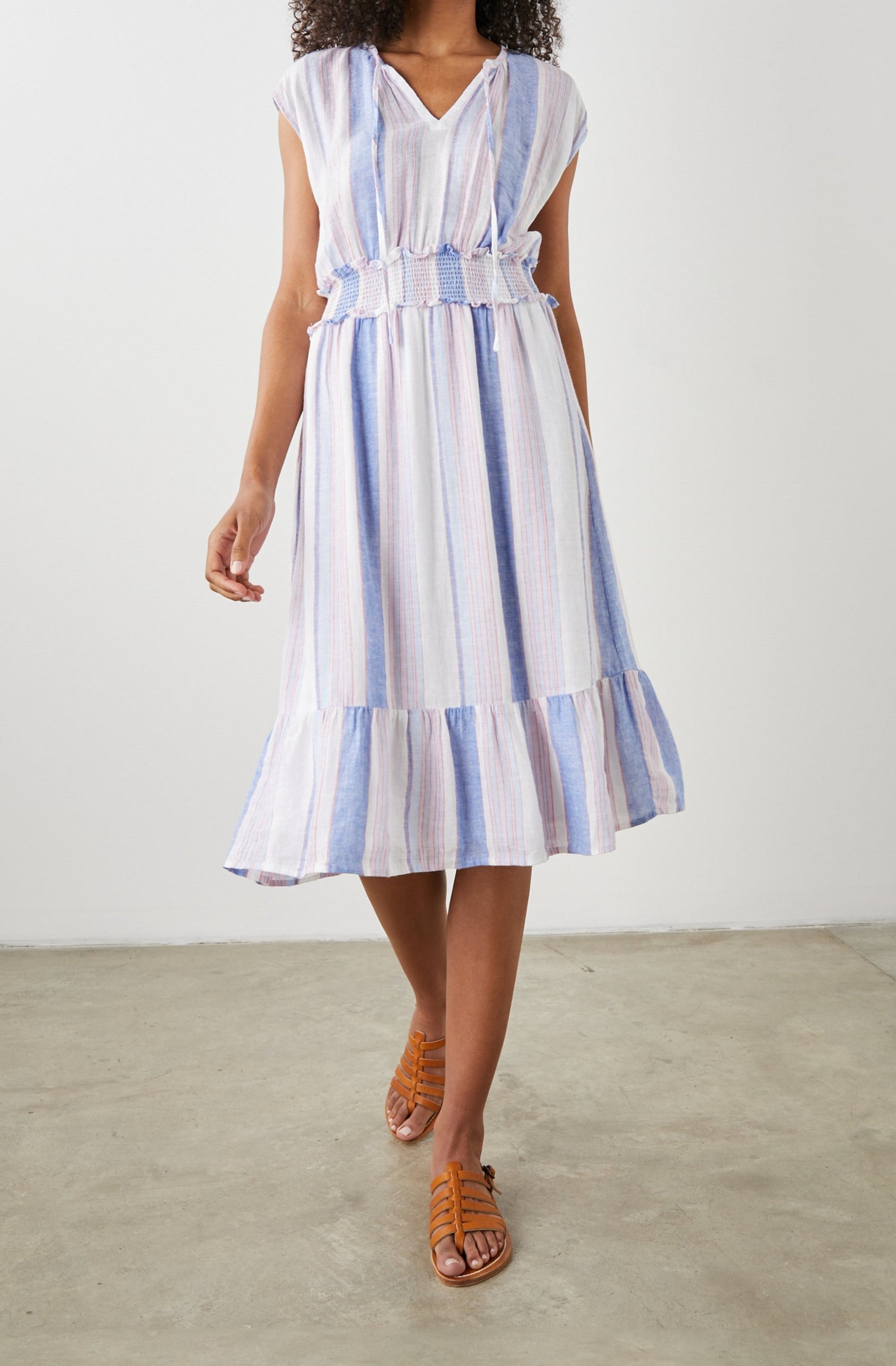 Ashlyn Short Sleeve Midi Dress with a V neck with Ties, a Smocked Waist and a Ruffle Tier at the Hem in Marini Stripe Colorway, Vertical Stripes in Pink and Blue on White - Front Full Body View Featured on Model