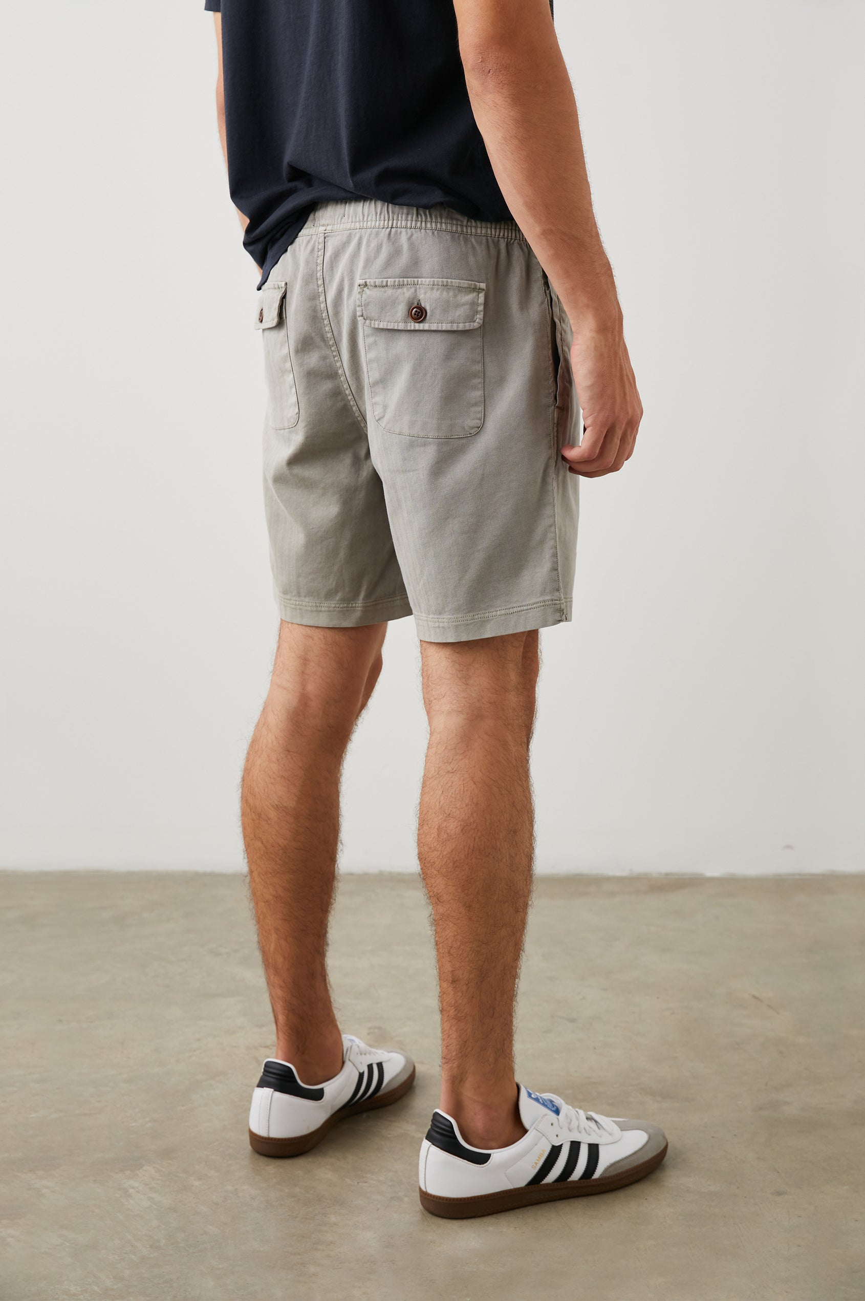 Cruz Shorts with a Drawstring Waist, Two Front Pockets, Two Back Button Flap Pockets in Washed Grey Colorway - Back View Featured on Model 