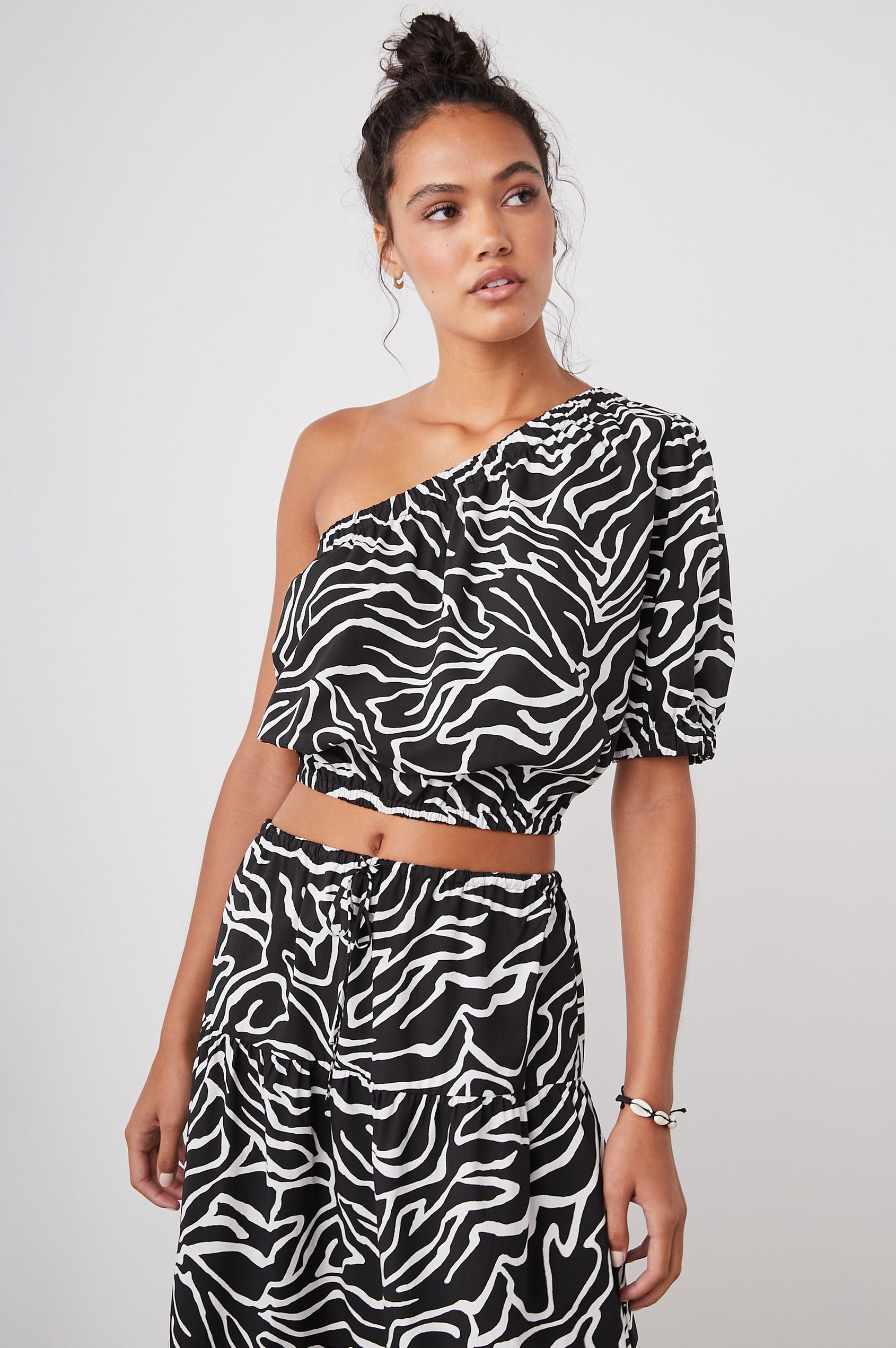 Evy Crop Top with an Asymmetrical Neckline, One Short Sleeve, and One Sleeveless, an Elasticized Hem and Cuff in Contour Lines Colorway, White Curves on Black - Front View Featured on Model 