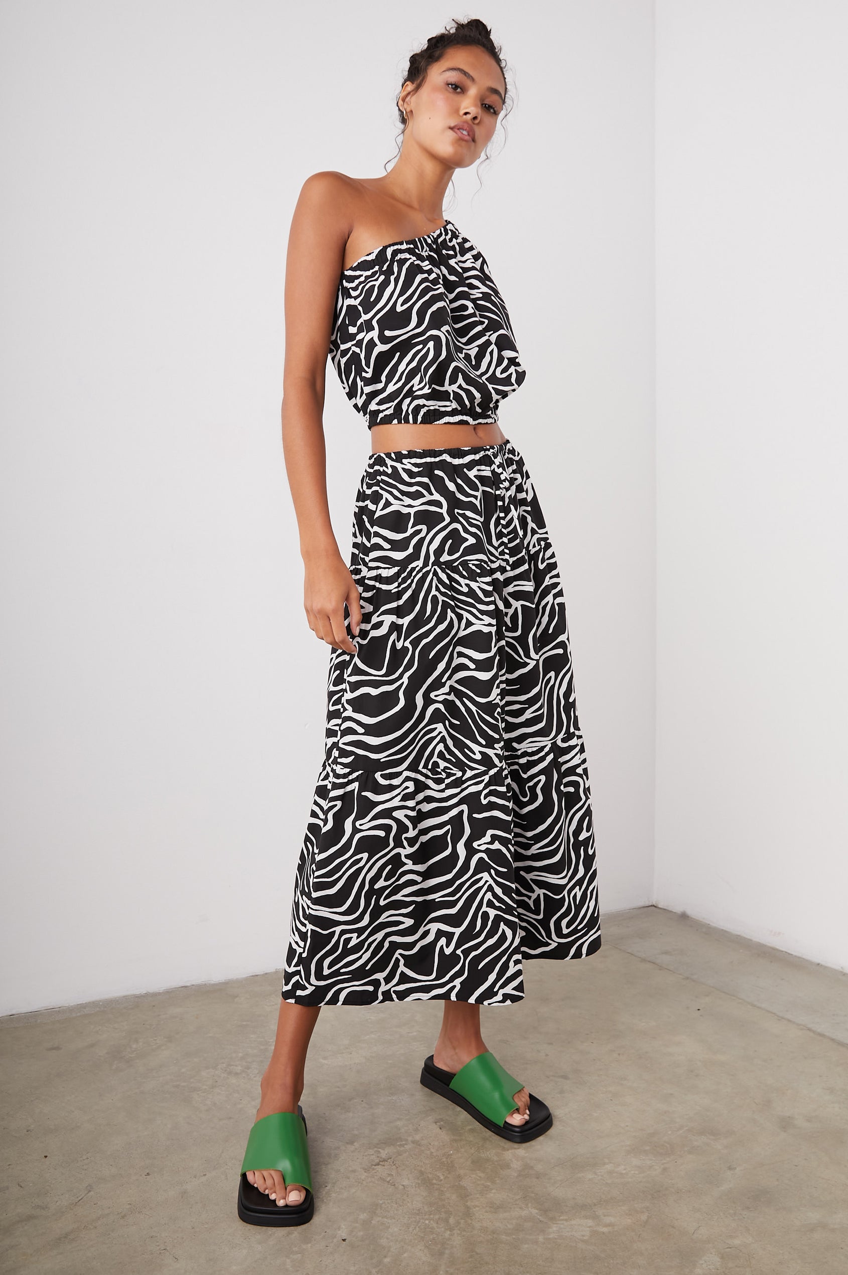 Evy Crop Top with an Asymmetrical Neckline, One Short Sleeve, and One Sleeveless, an Elasticized Hem and Cuff in Contour Lines Colorway, White Curves on Black - Front Full Body View Featured on Model 